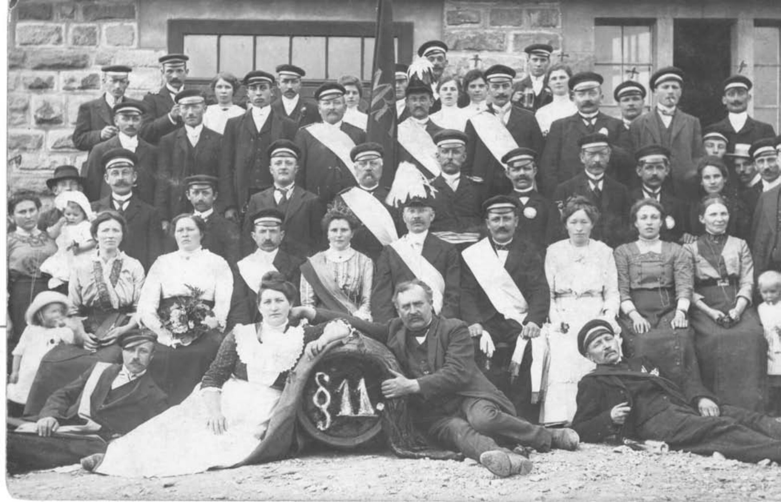 Ein Gruppenfoto in Schwarz-Weiß zeigt die Mitglieder des Vereins und ihre Frauen beim Schützenfest 1914.