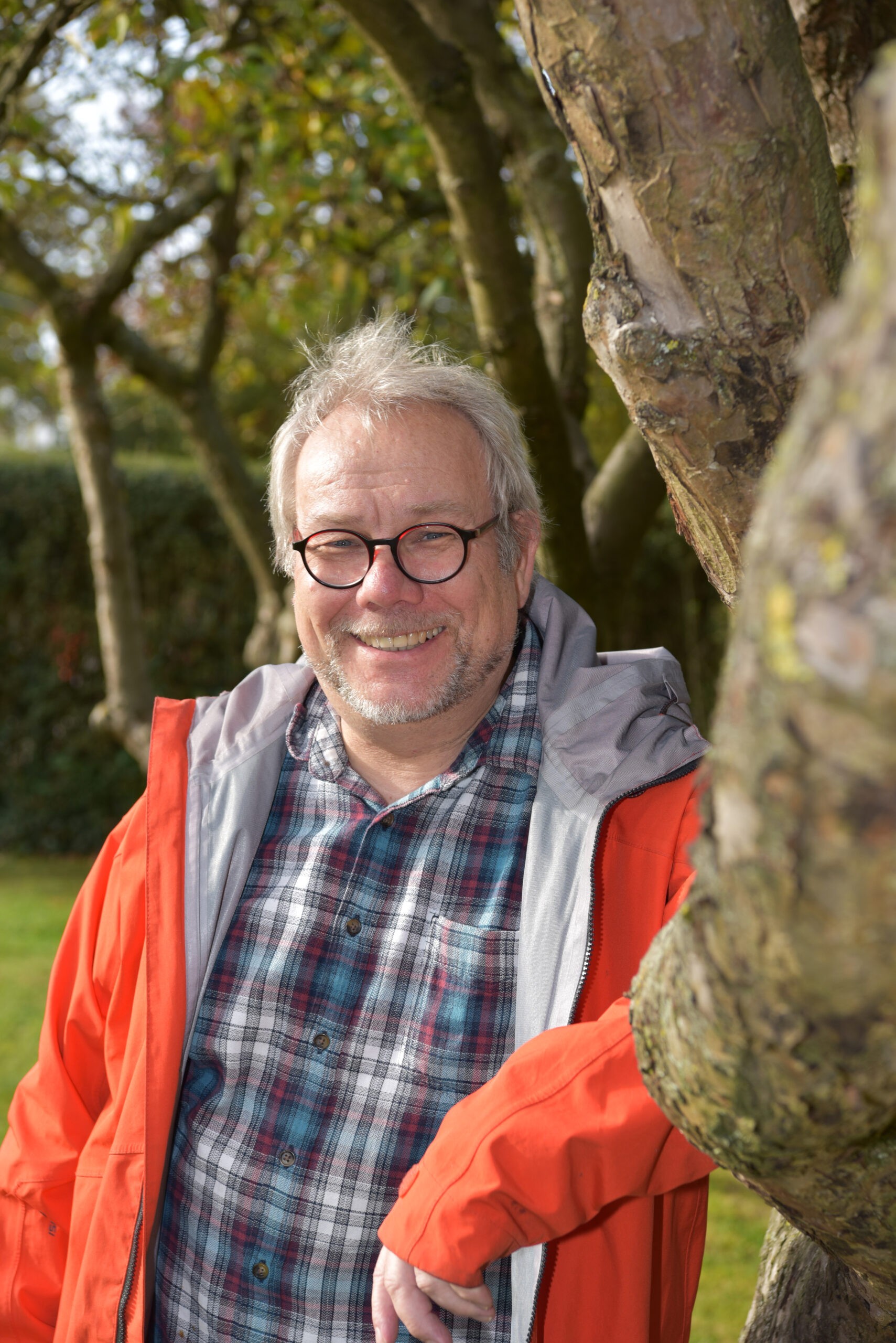Gemeindereferent Ulrich Martinschledde lehnt lächelnd an einem Baum