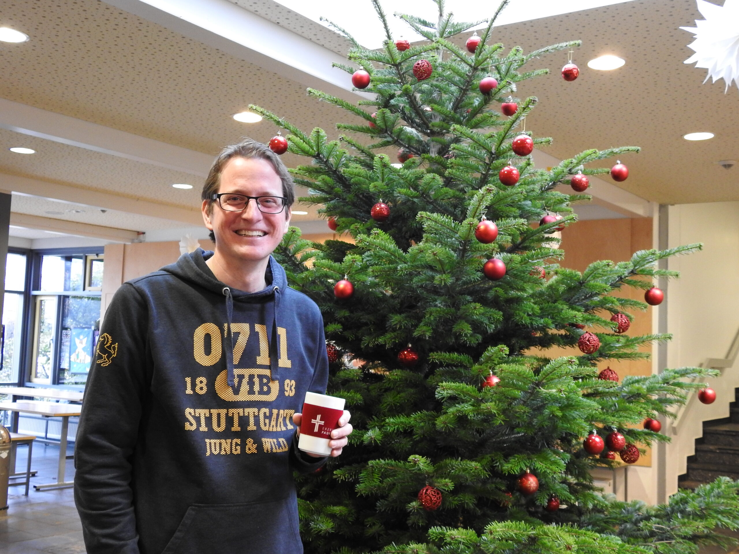 Christoph Scheppe vor einem mit Christbaumkugeln geschmückten Tannenbaum