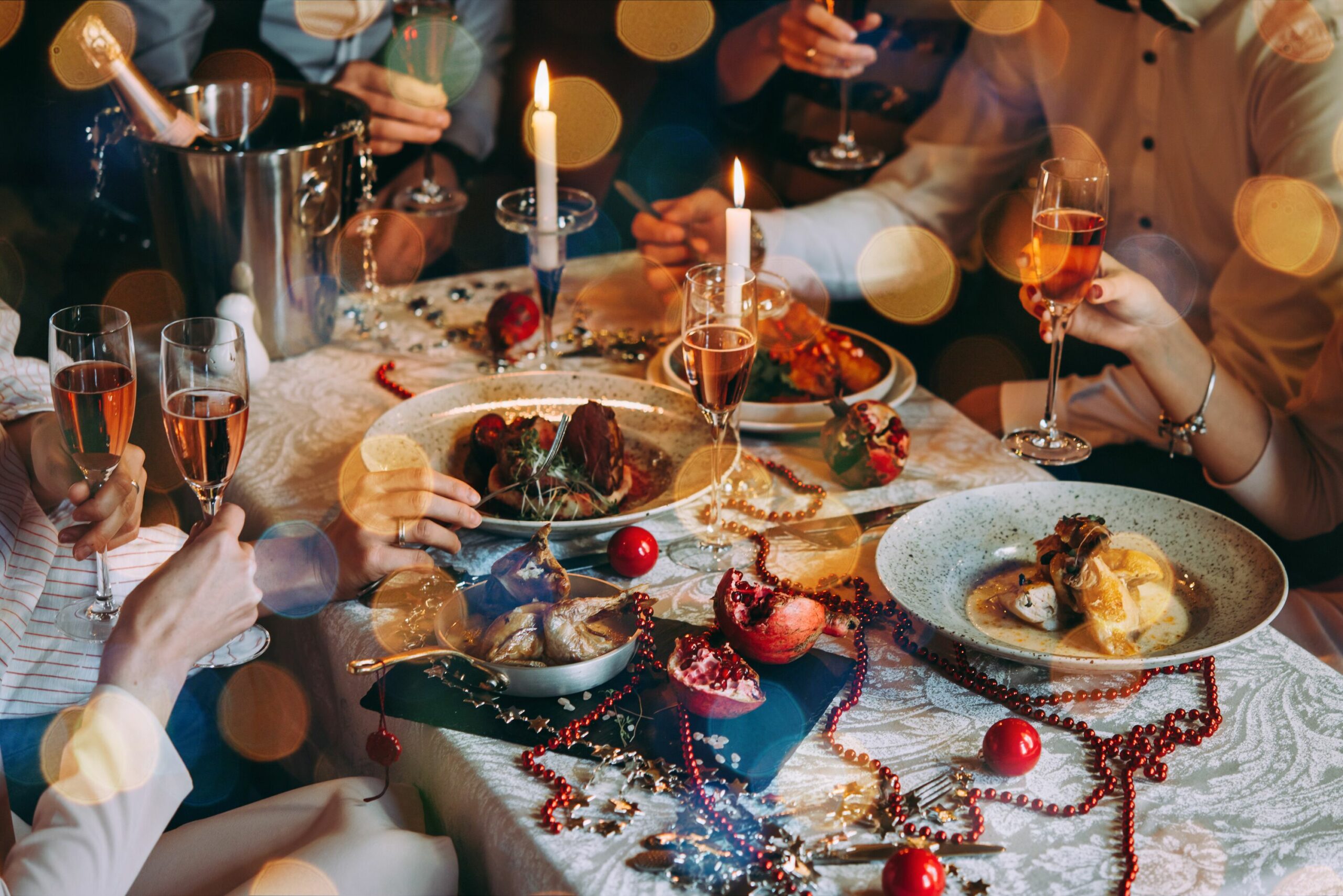 Menschen sitzen für ein gemeinsames Essen an Heiligabend um einen festlich gedeckten Tisch.