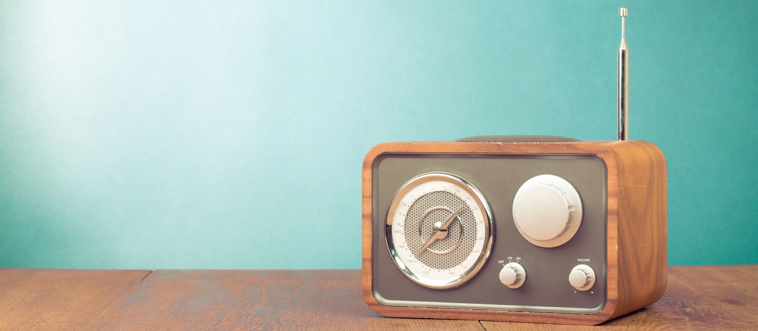 Altes Radio-Gerät vor türkiser Wand auf Holz