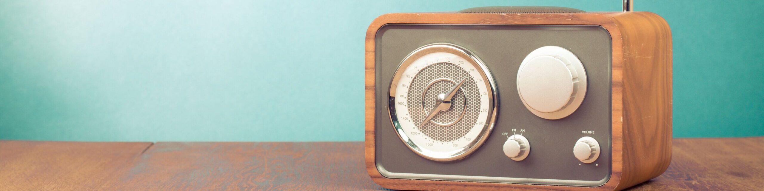 Altes Radio-Gerät vor türkiser Wand auf Holz