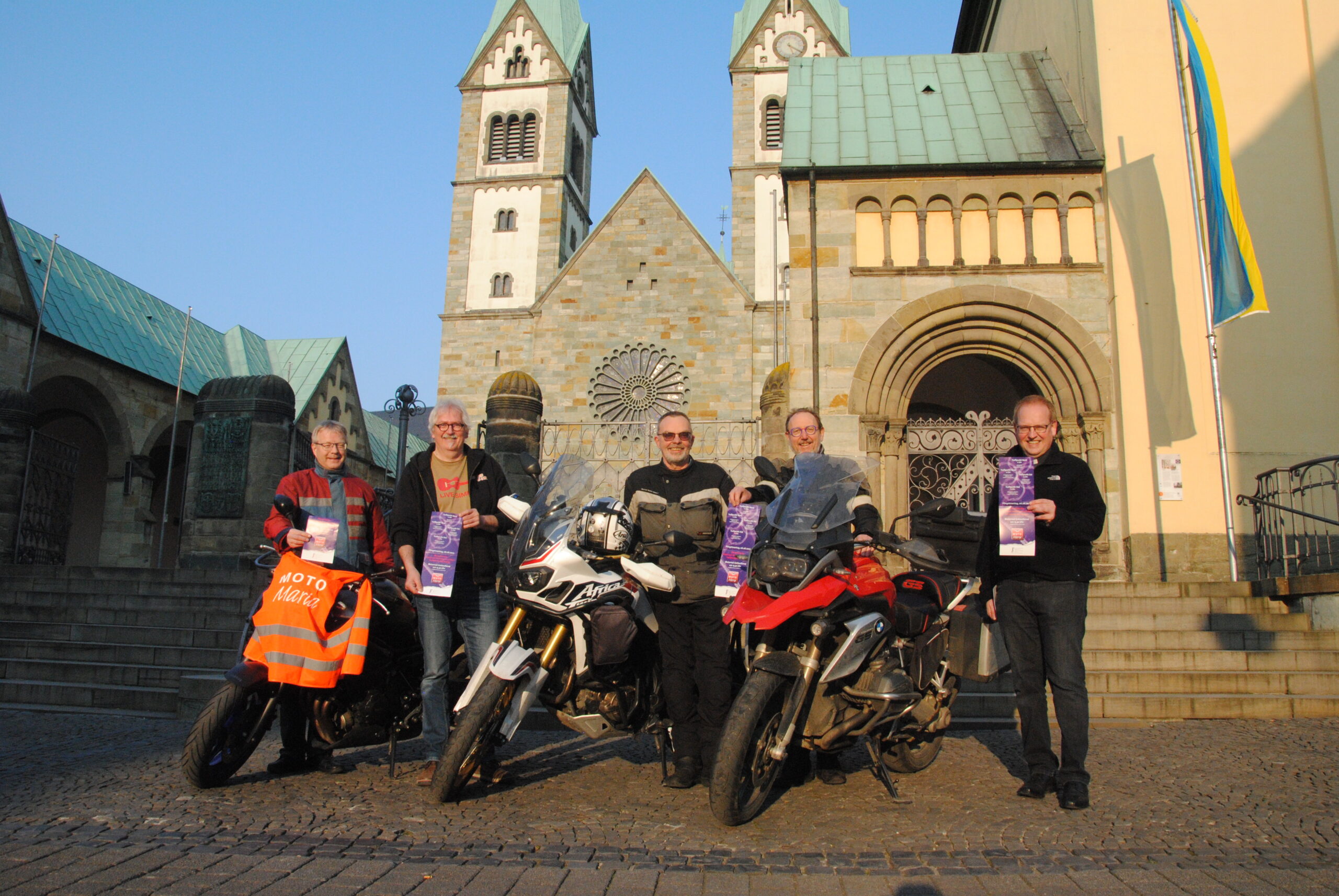 Menschen mit Motorrädern vor Kirche