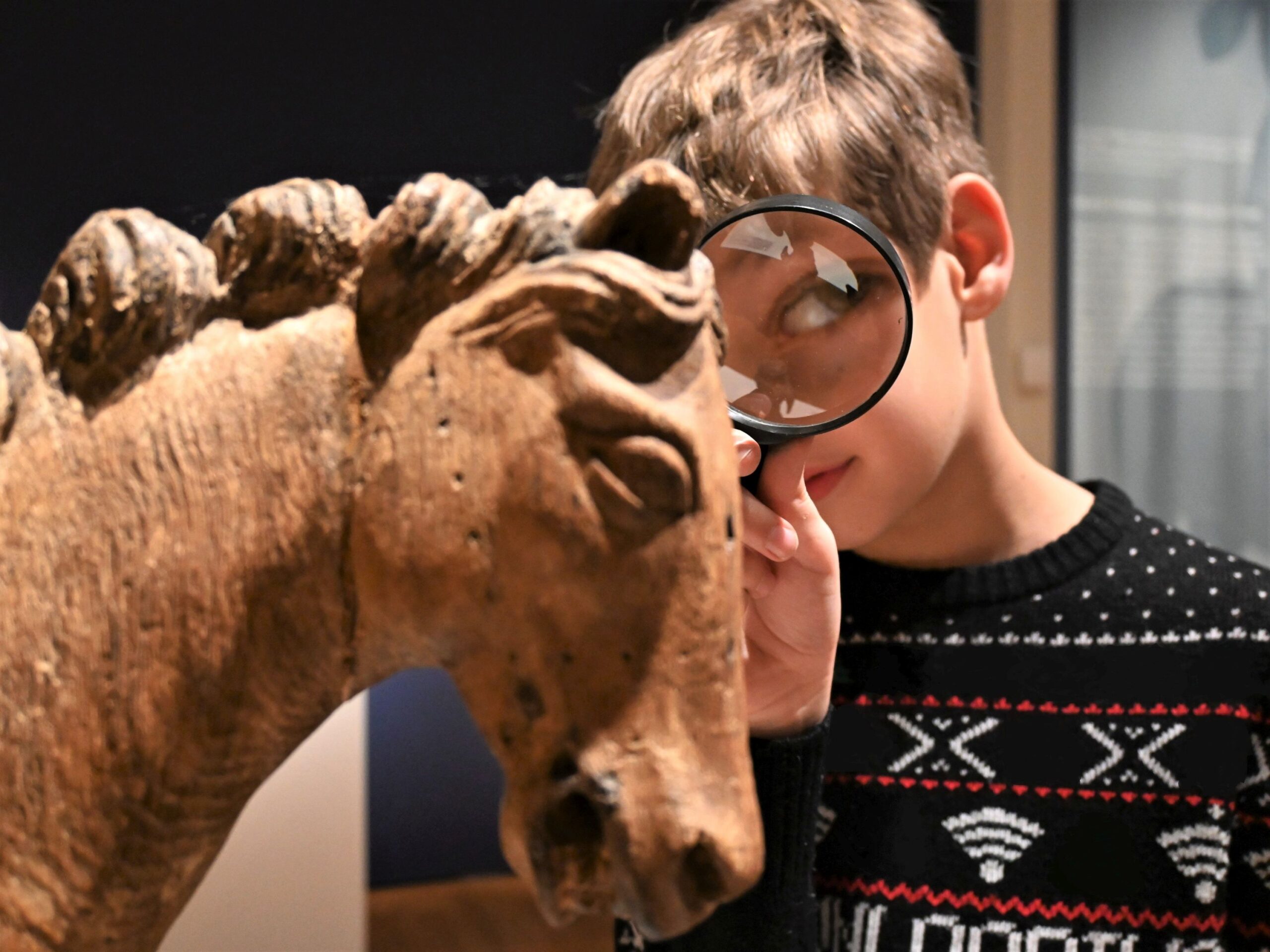 Junge mit Lupe an Skulptur