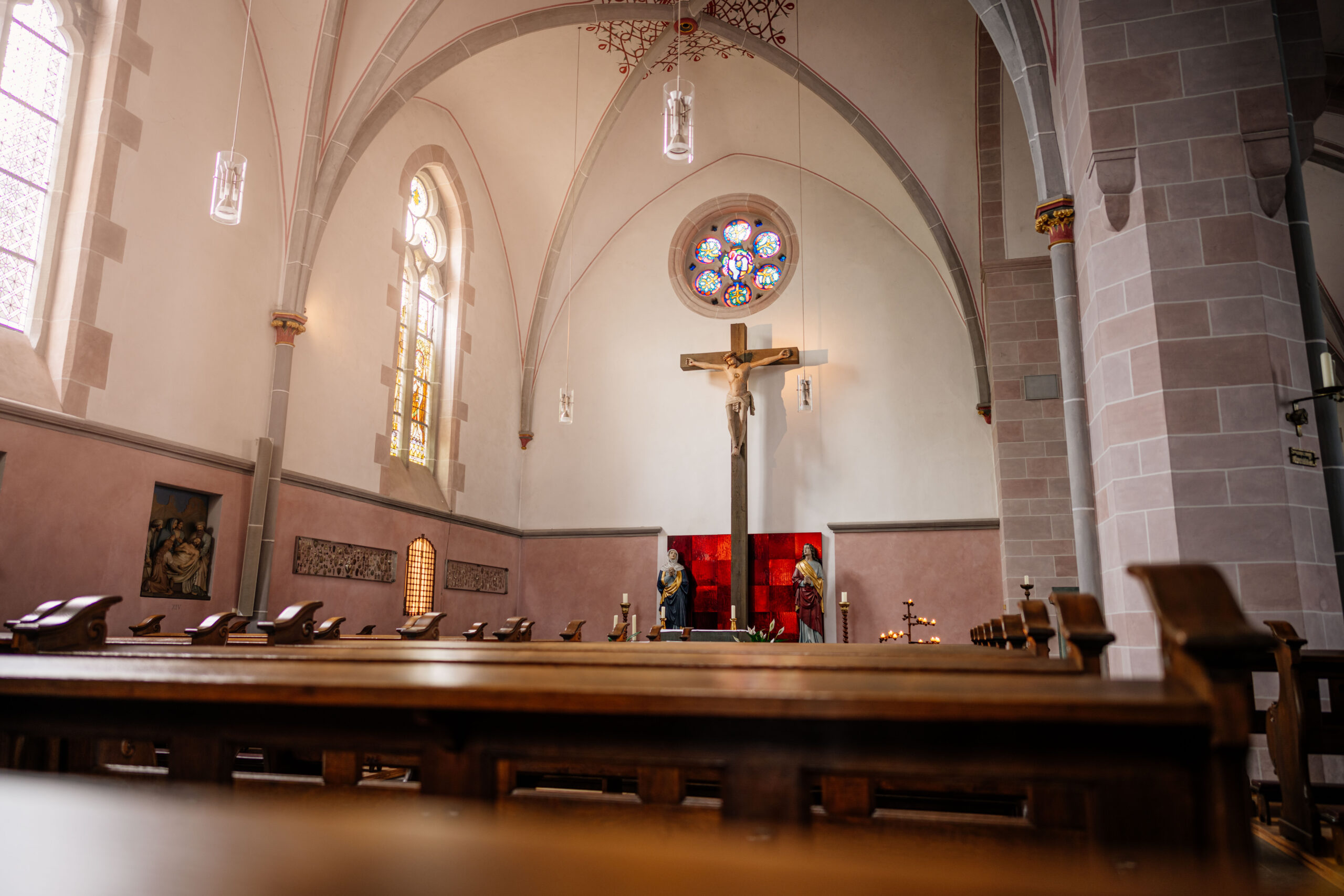 Das große Kreuz im Kreuzschiff von St. Johannes Baptist. Links das Buntglasfenster mit der heiligen Helena und Bischof Macarius.