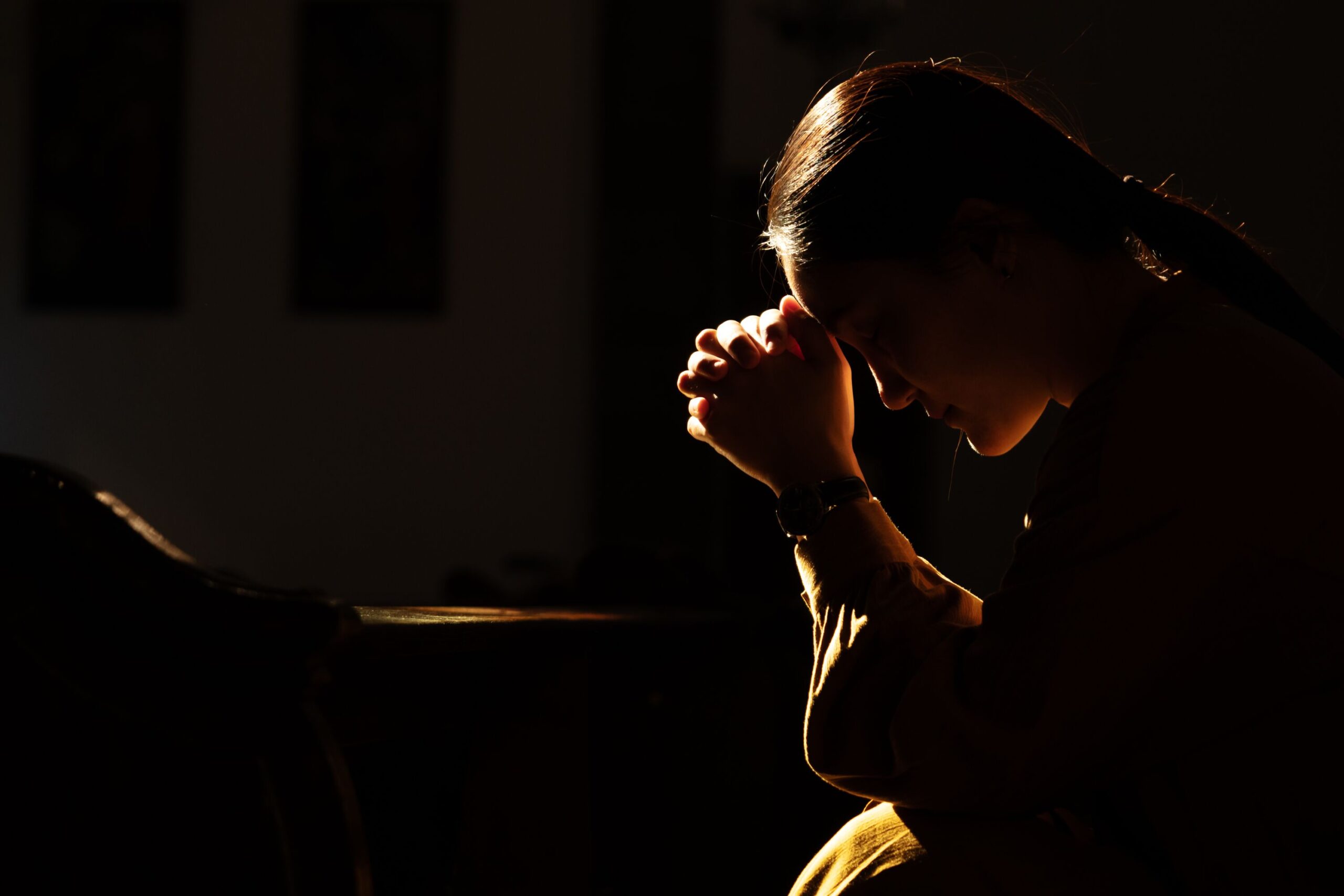 Frau betet in dunkler Umgebung