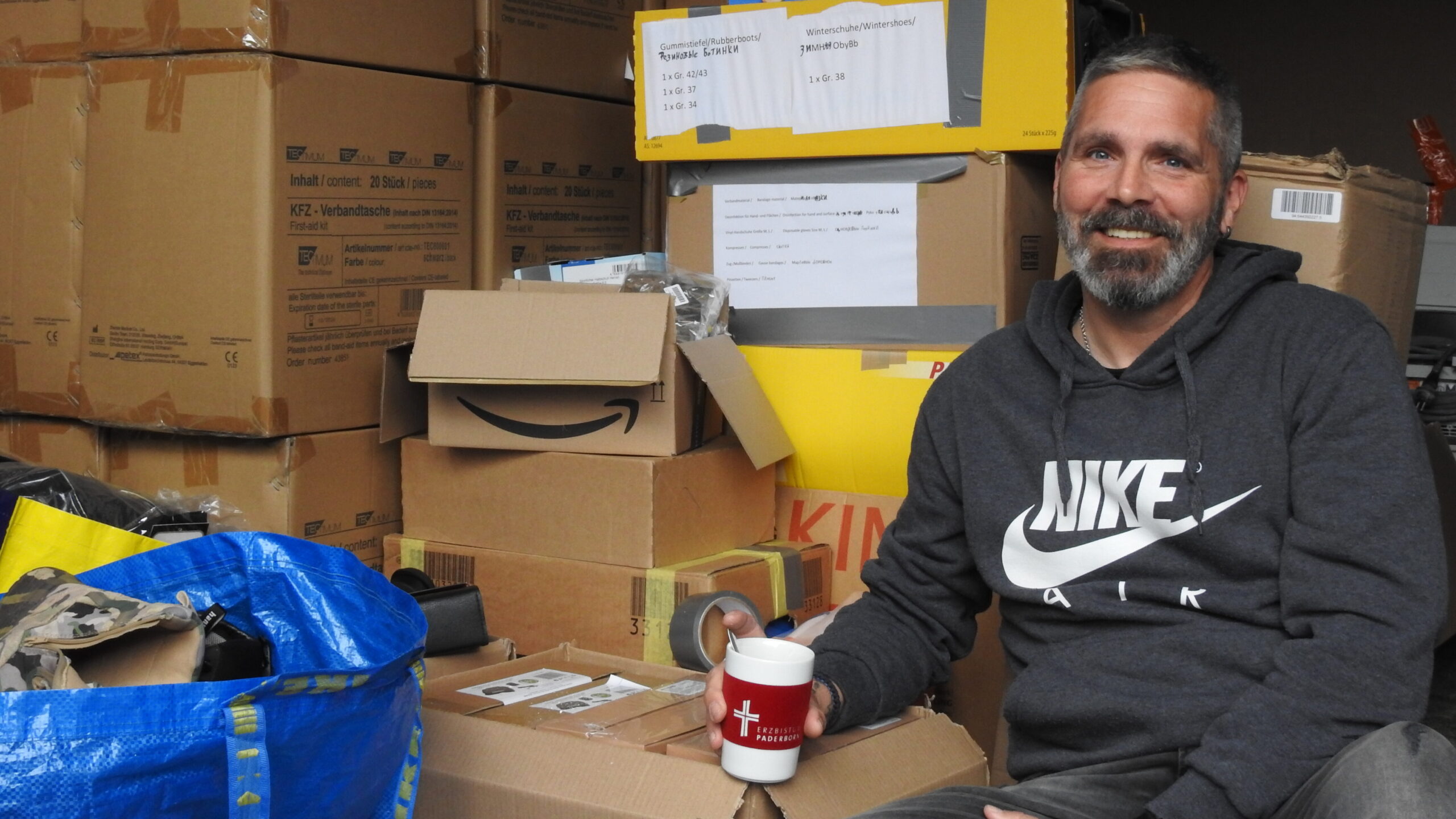 Christoph Weingarten vor Hilfsgütern in Kartons verpackt