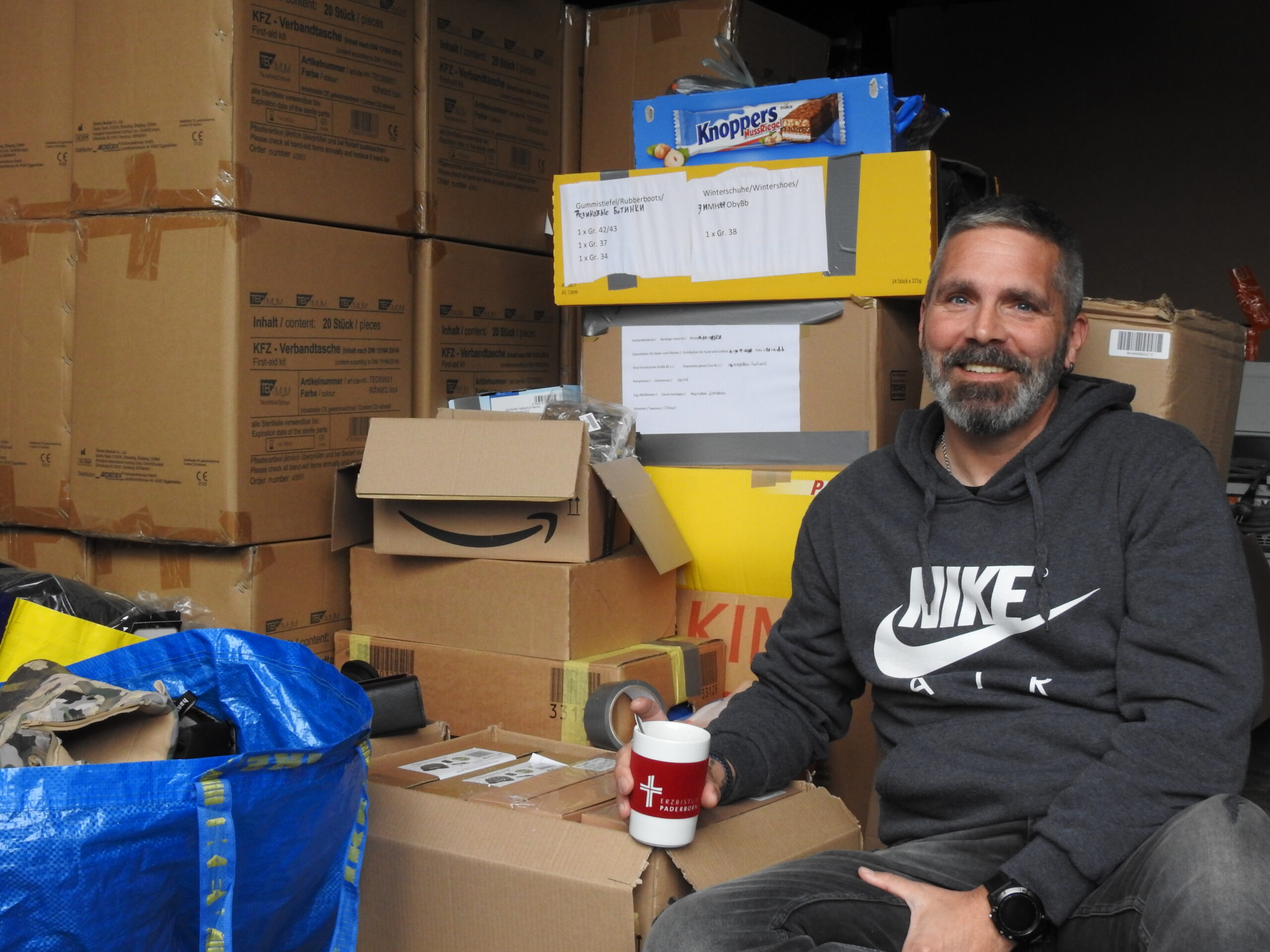 Christoph Weingarten vor Hilfsgütern in Kartons verpackt