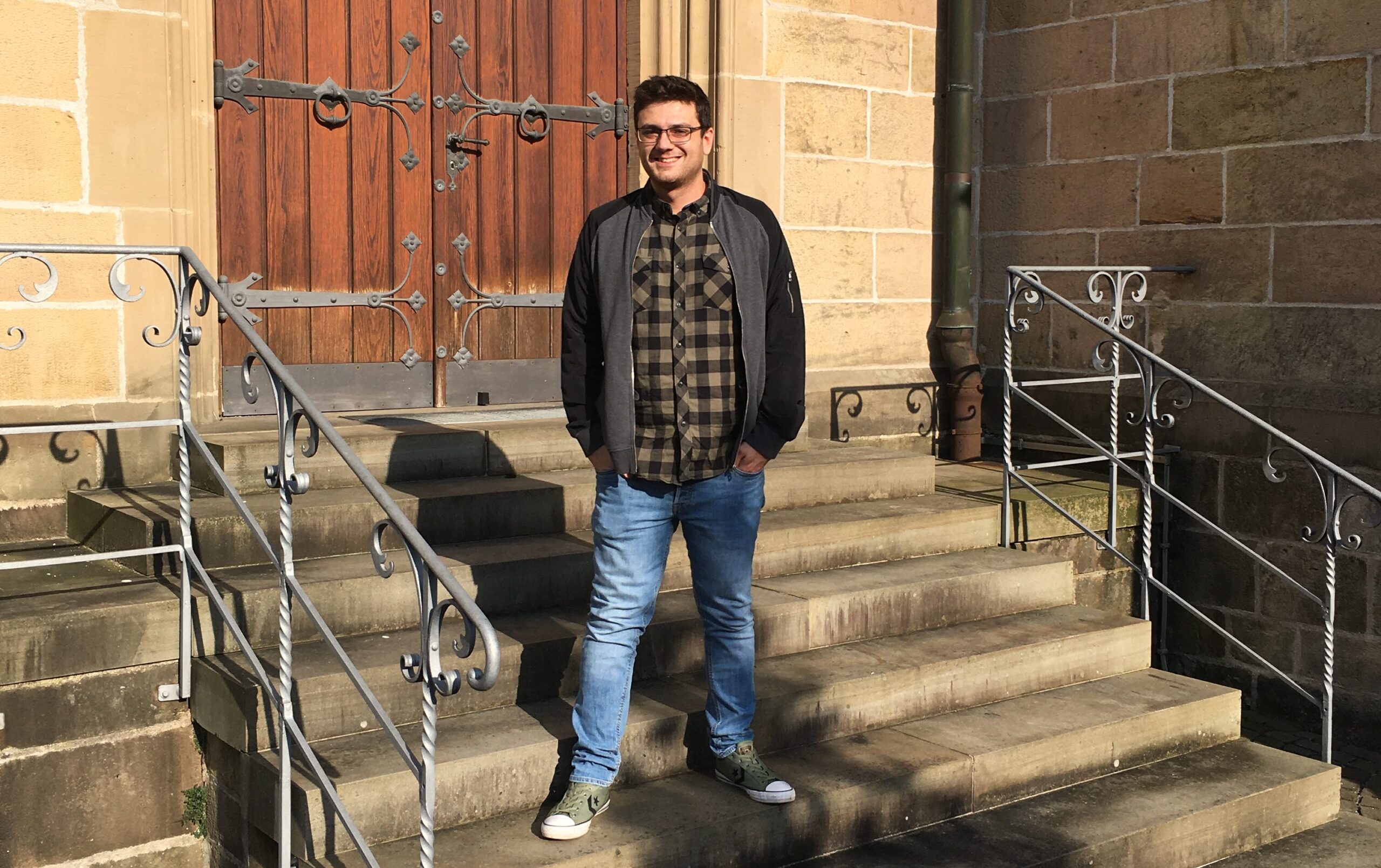 Gemeindereferent Daniel Feldmann steht auf den Treppen zu einer Kirche