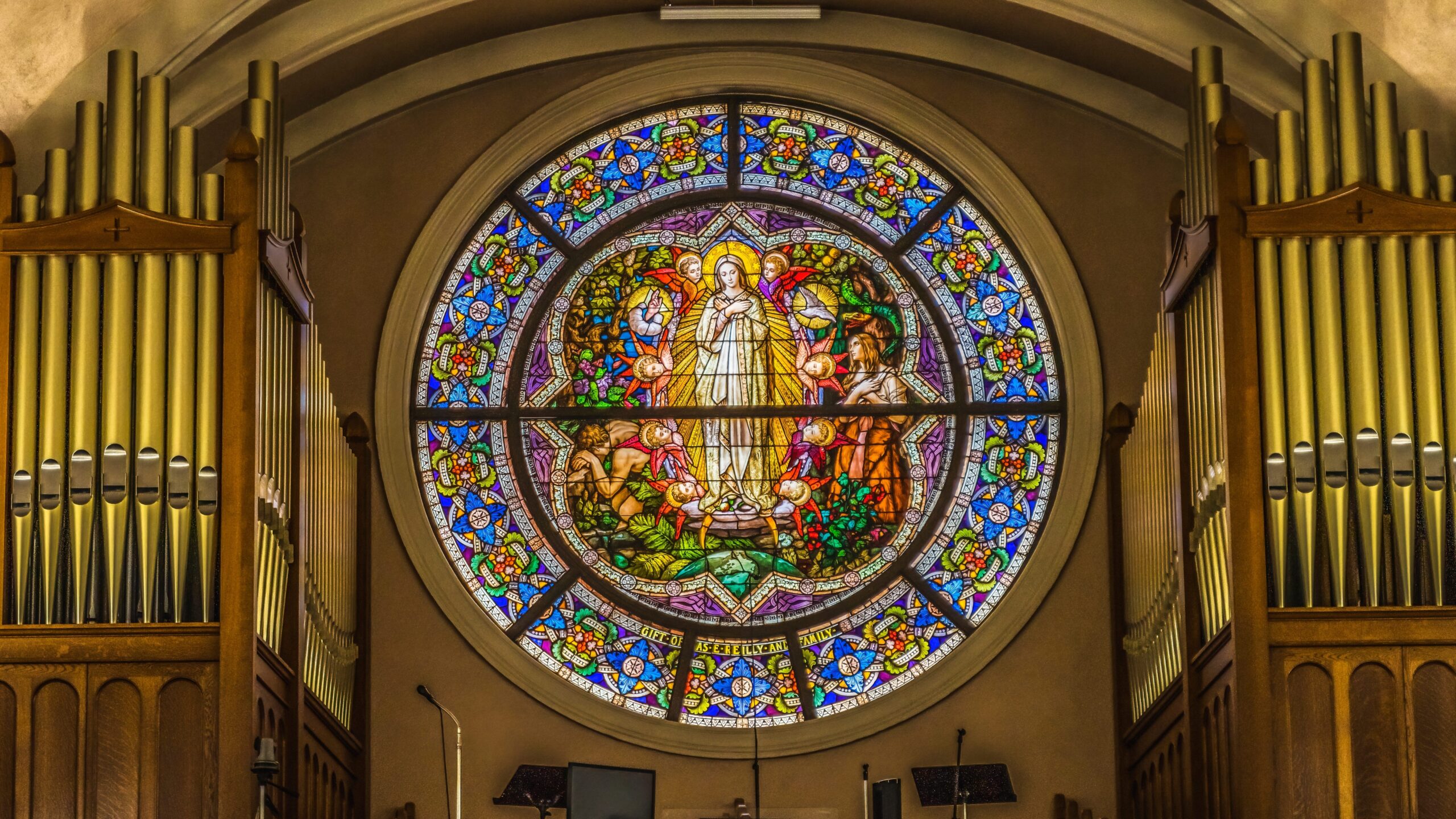 Von Orgel eingerahmtes Kirchenfenster. Das Fenster zeigt Maria.
