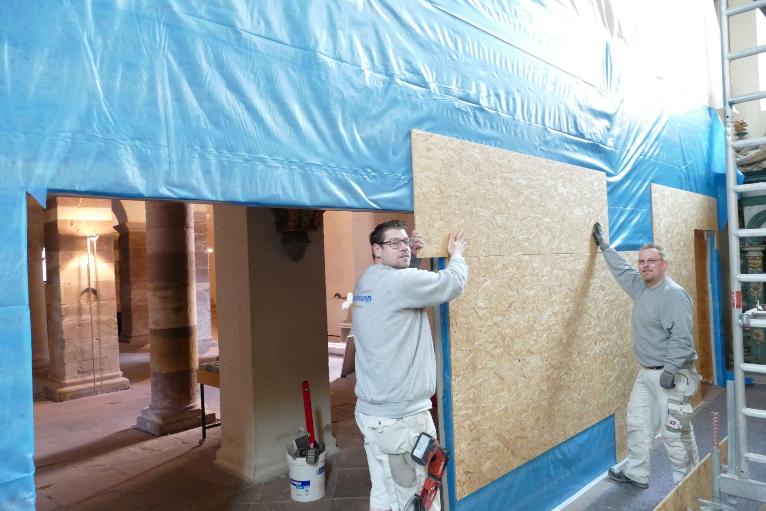 Unterhalb der Orgelempore haben Fachhandwerker der Firma Laackmann Trockenbau aus Bad Driburg die Staubschutzwand angebracht. Das war, obwohl sie viel rumkommen, etwas Besonderes, resümieren Christian Mahs (links) und Sascha Böker.