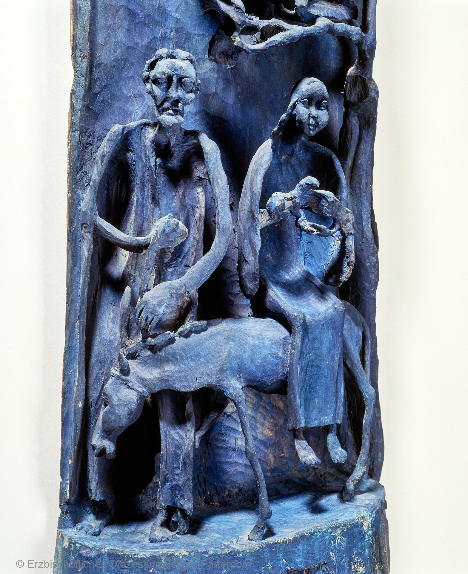 Eine blaue Holzstatue zeigt Josef, Maria und das Jesuskind auf der Flucht nach Ägypten