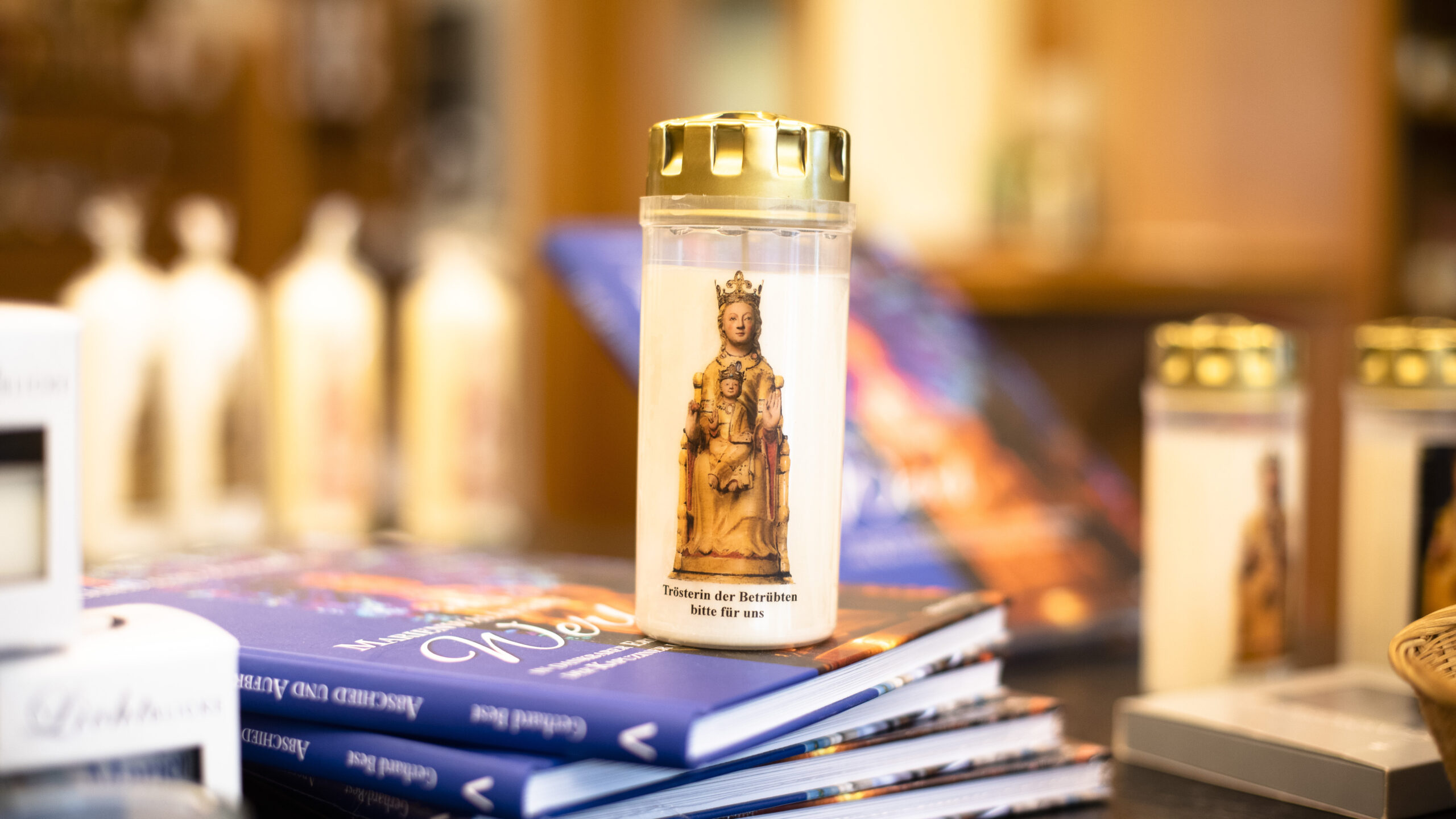 Eine Kerze steht auf einem Stapel Büchern in dem Laden des Pilgerbüros