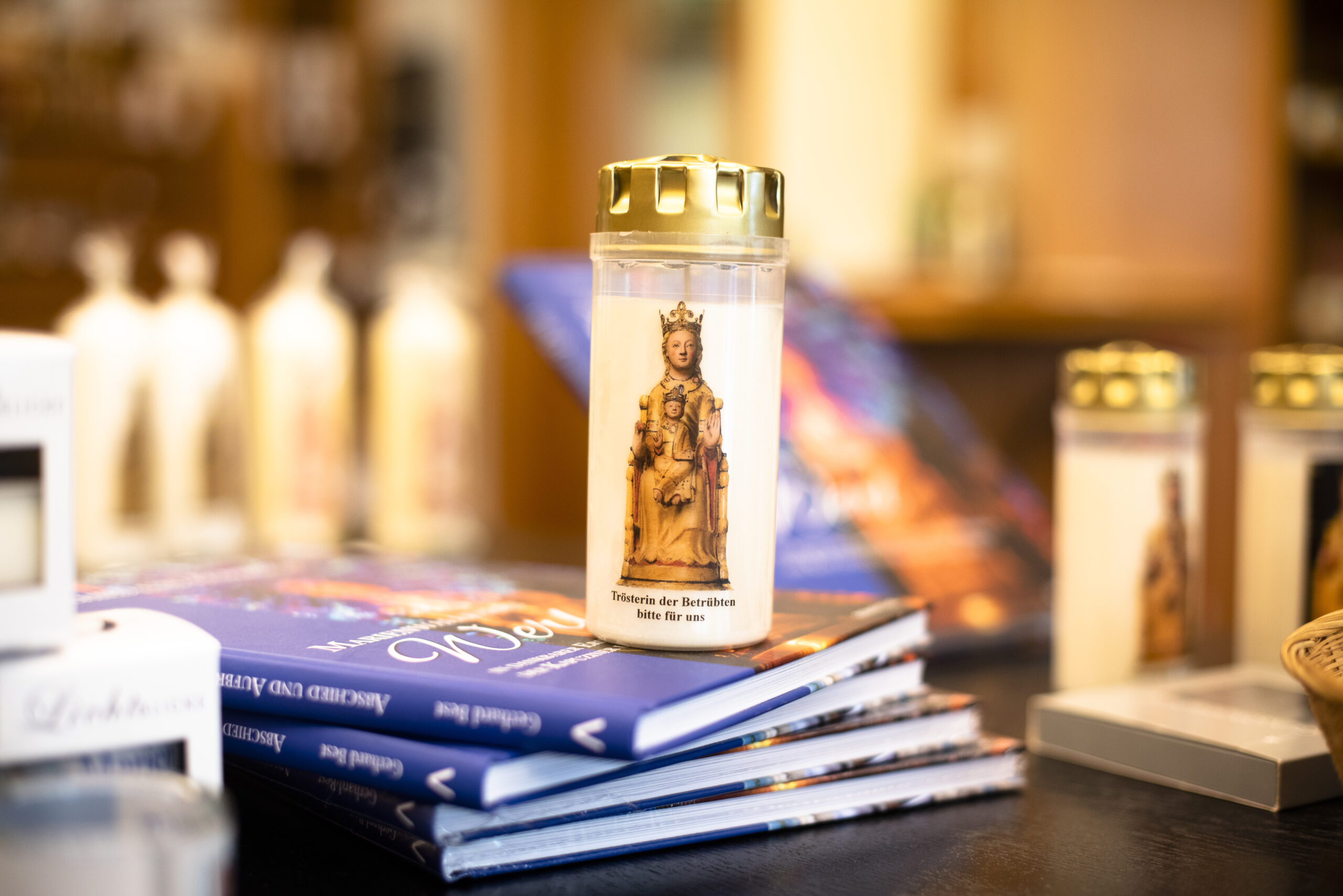 Eine Kerze steht auf einem Stapel Büchern in dem Laden des Pilgerbüros