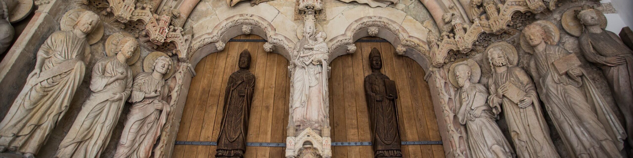 Im Zentrum des Paradiesportals sieht man die drei Patrone des Paderborner Domes: Die Gottesmutter Maria mit dem Jesuskind auf dem Arm, rechts von ihr der heilige Liborius mit einem Buch in der Hand, links von ihr der heilige Kilian