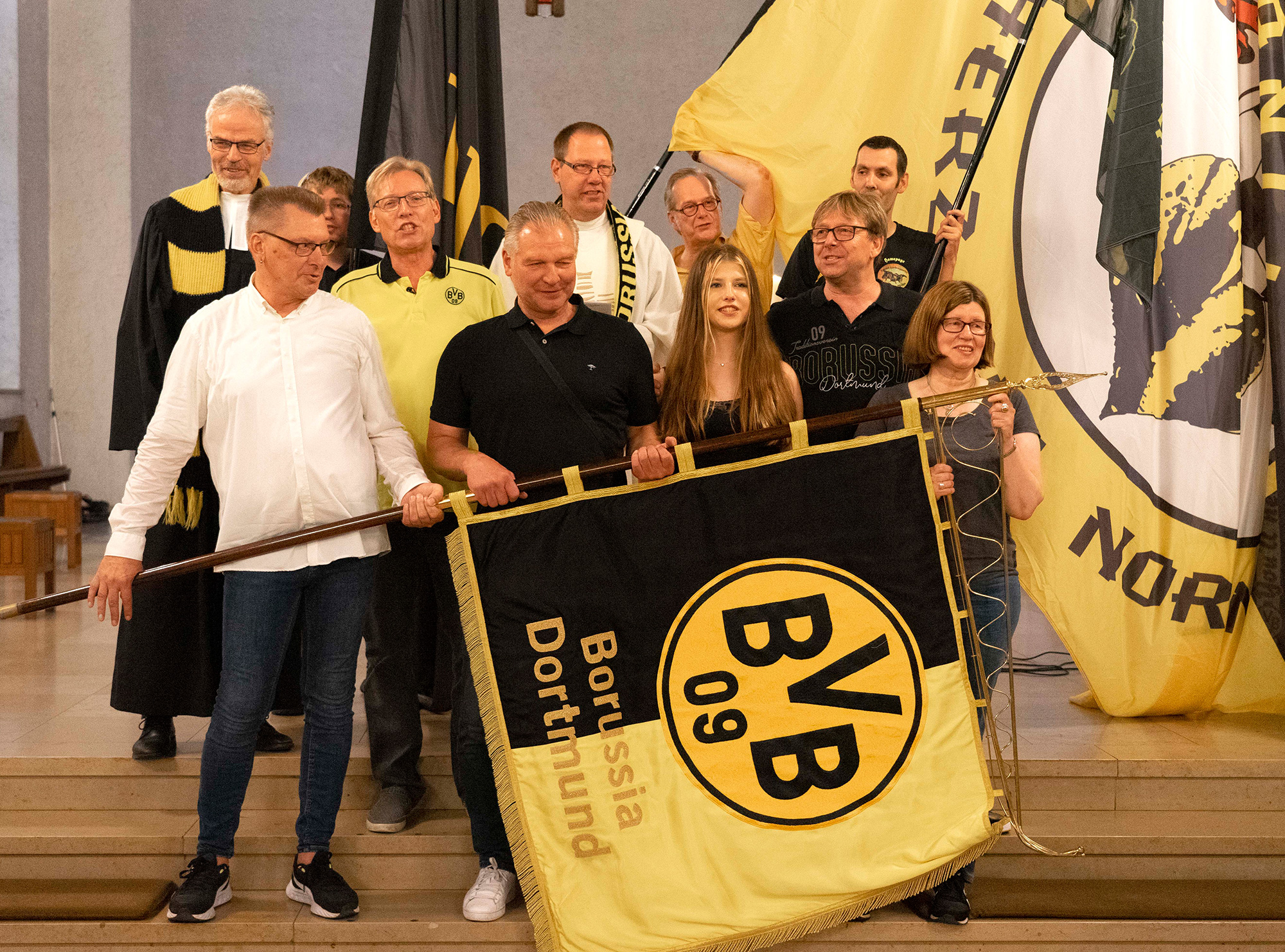 Am Ende präsentierten die Mitwirkenden des Gottesdienstes zur Saisoneröffnung die BVB-Traditionsfahne, hier mit Wolfgang „Teddy“ de Beer, früherer Fußballtorhüter und Torwarttrainer (vorne 2.v.l.). Foto: Michael Bodin / Erzbistum Paderborn