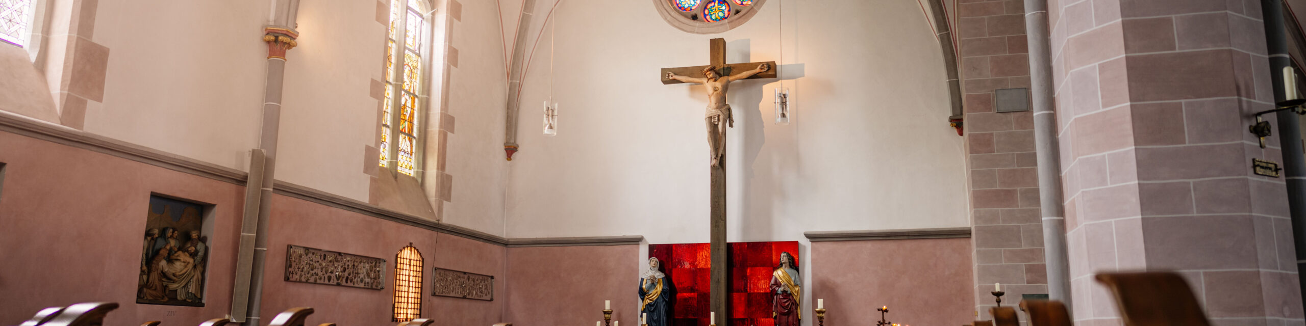 Das große Kreuz im Kreuzschiff von St. Johannes Baptist. Links das Buntglasfenster mit der heiligen Helena und Bischof Macarius.