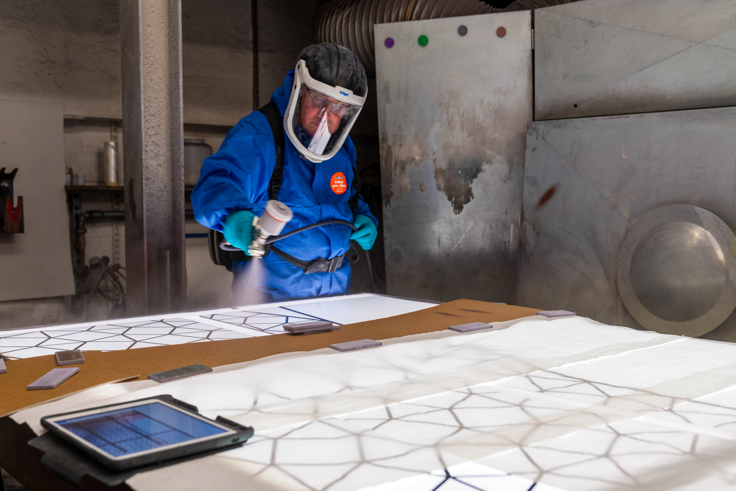 Ein Mitarbeiter der Glasmalerei Peters Studios bearbeitet eine Glasfläche, um einen Entwurf von Angelika Weingardt für ein Kirchenfenster umzusetzen.