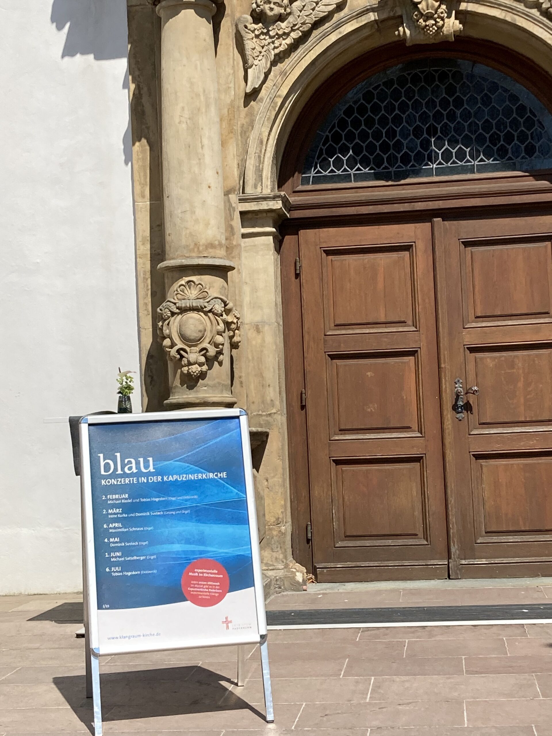 Plakat der Reihe "blau" vor der Kapuzinerkirche Paderborn