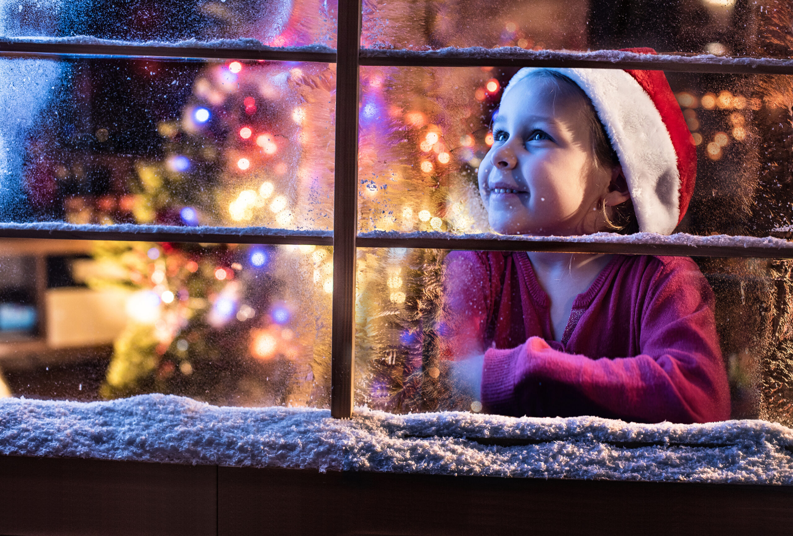 Mädchen wartet auf Weihnachten am Fenster