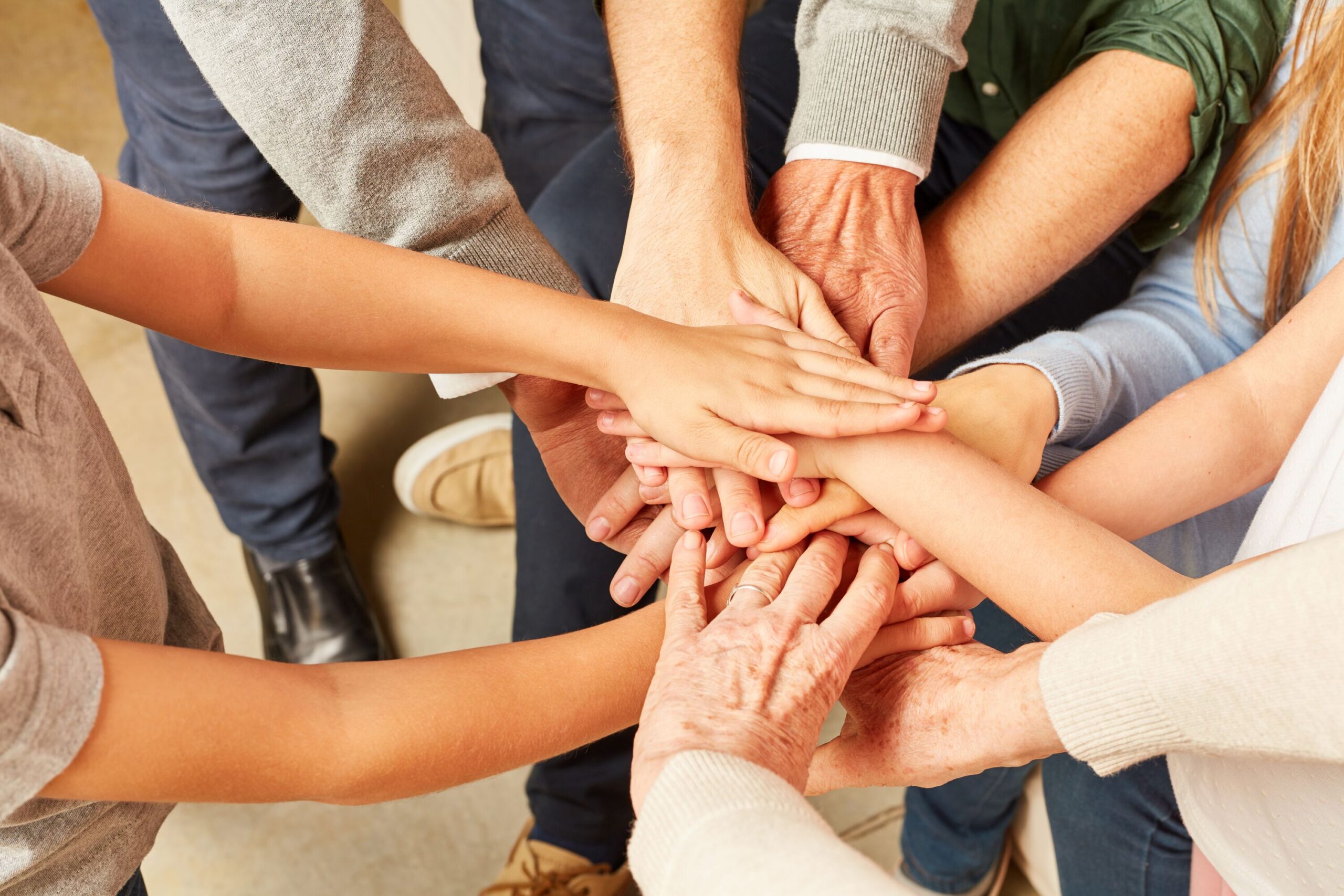 Menschen legen Hände aufeinander als Symbol für Gemeinschaft.