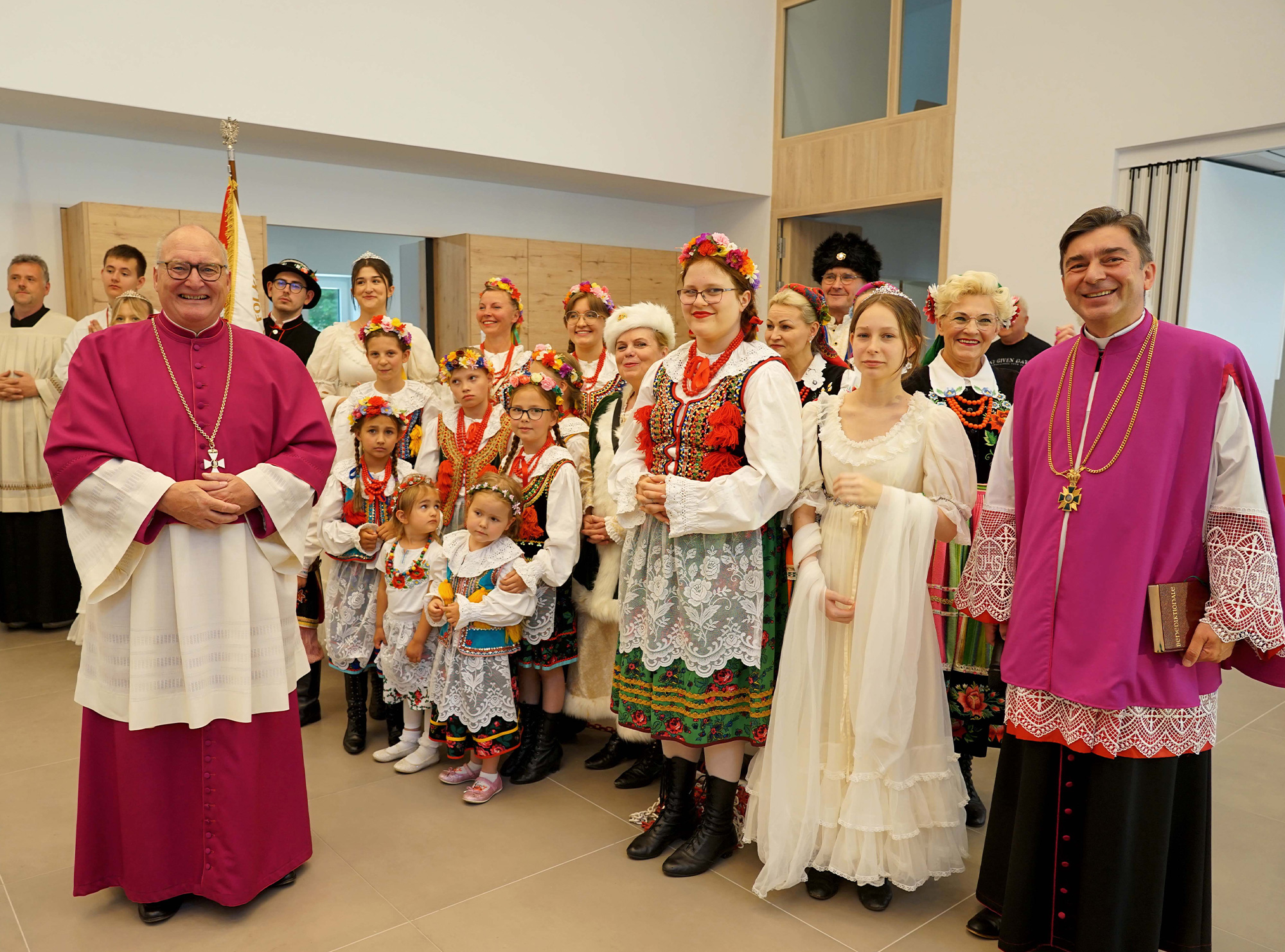 Im Erdgeschoss des neuen Pfarrzentrums steht der polnischen Gemeinde ein großer Saal zur Verfügung. Domkapitular Propst Andreas Coersmeier (links) und Pfarrer Bartlomiej Ilkow (rechts) freuen sich mit der Trachtengruppe und den vielen anderen Gruppen der Gemeinde über die neuen Möglichkeiten. Foto: Michael Bodin / Erzbistum Paderborn