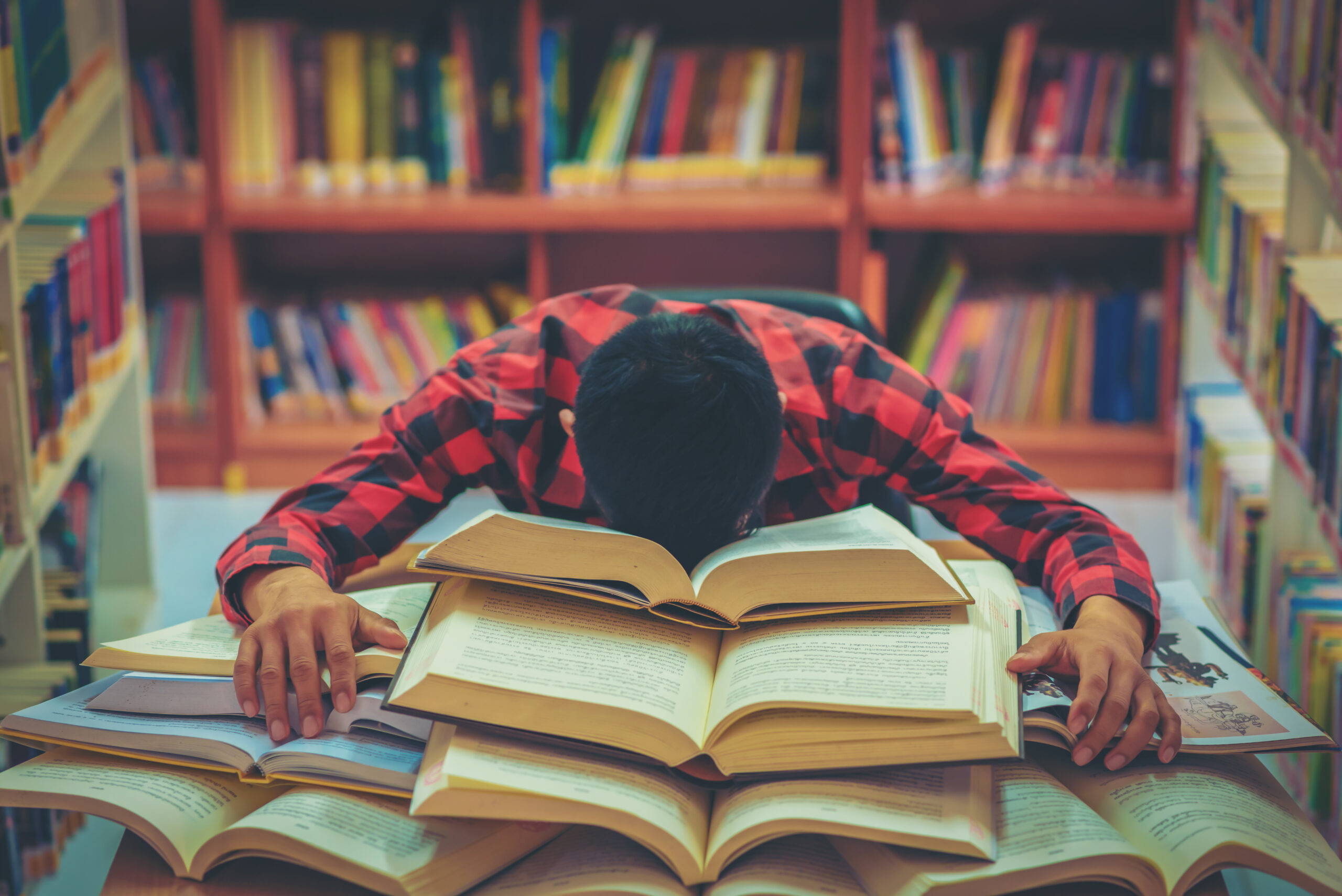 Ein überforderter Schüler auf seinen Büchern