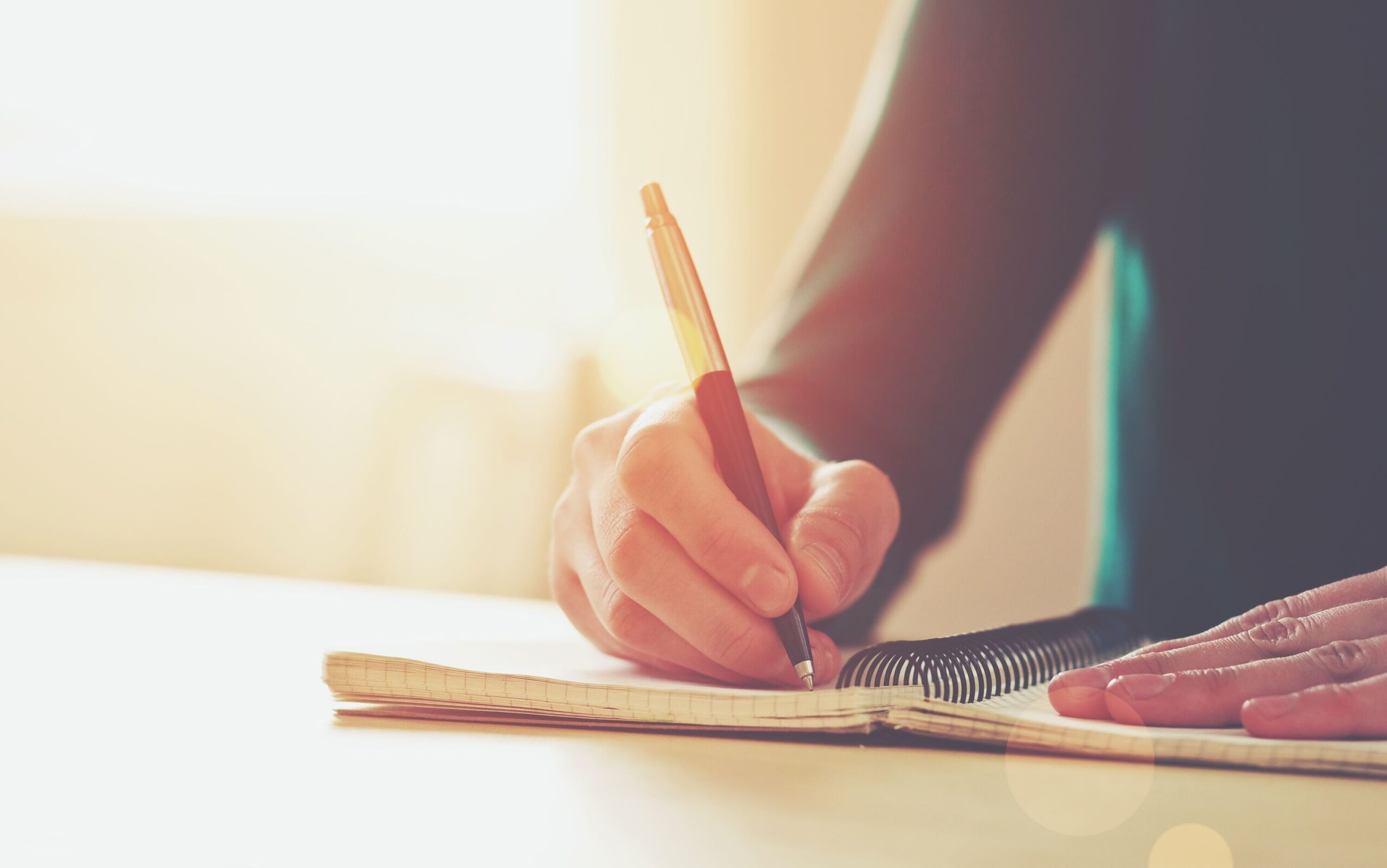 Weibliche Hände mit Stift schreiben auf Notizbuch