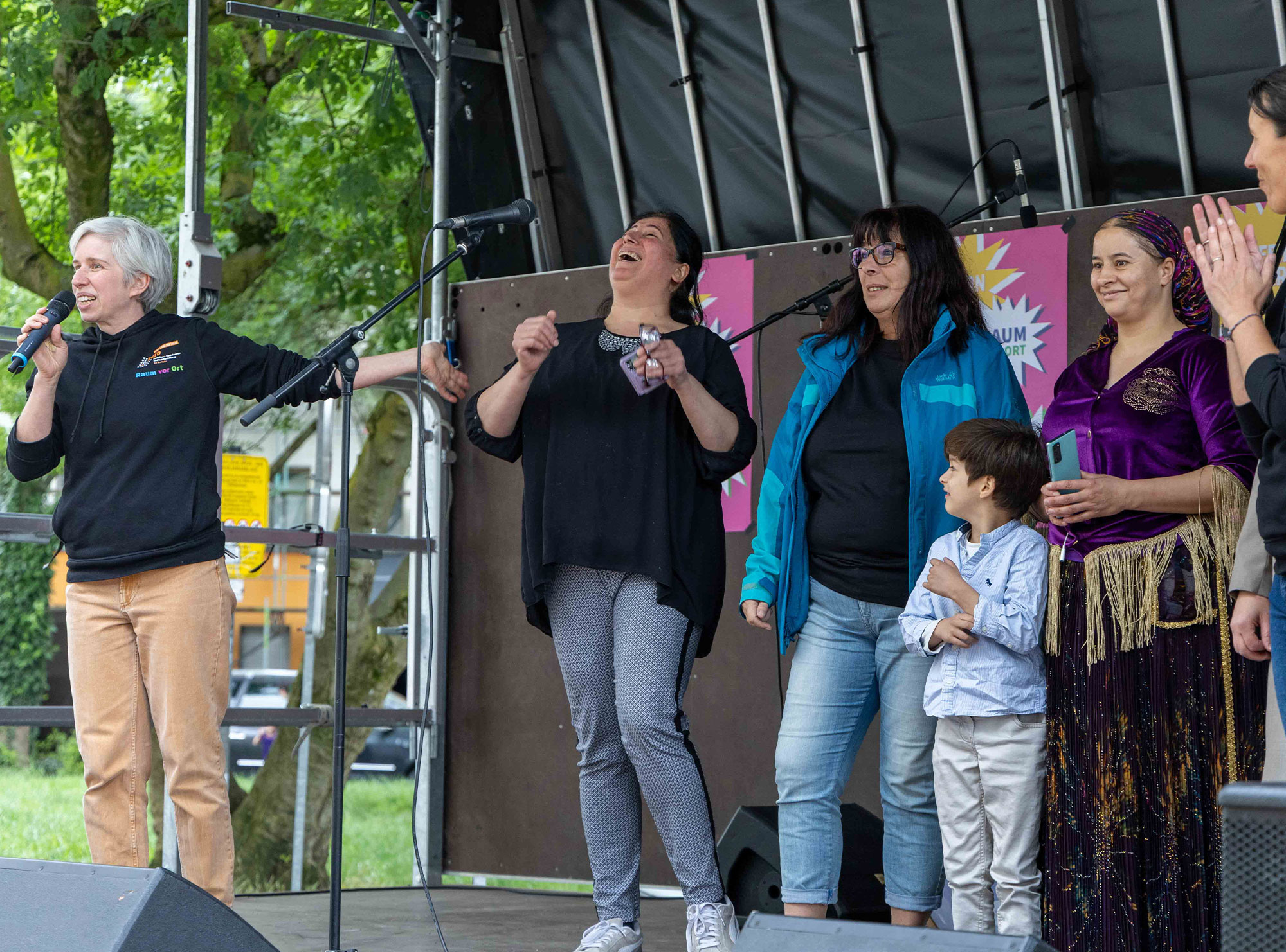 Nora Oertel Ribeiro (links), Bildungsreferentin der Katholischen Erwachsenen- und Familienbildung An der Ruhr (kefb), begrüßte zahlreiche Mitwirkende auf der Bühne beim Fest zum zehnjährigen Bestehen vom Raum vor Ort in der Missundestraße in Dortmund Nord. Foto: © Andreas Andresen