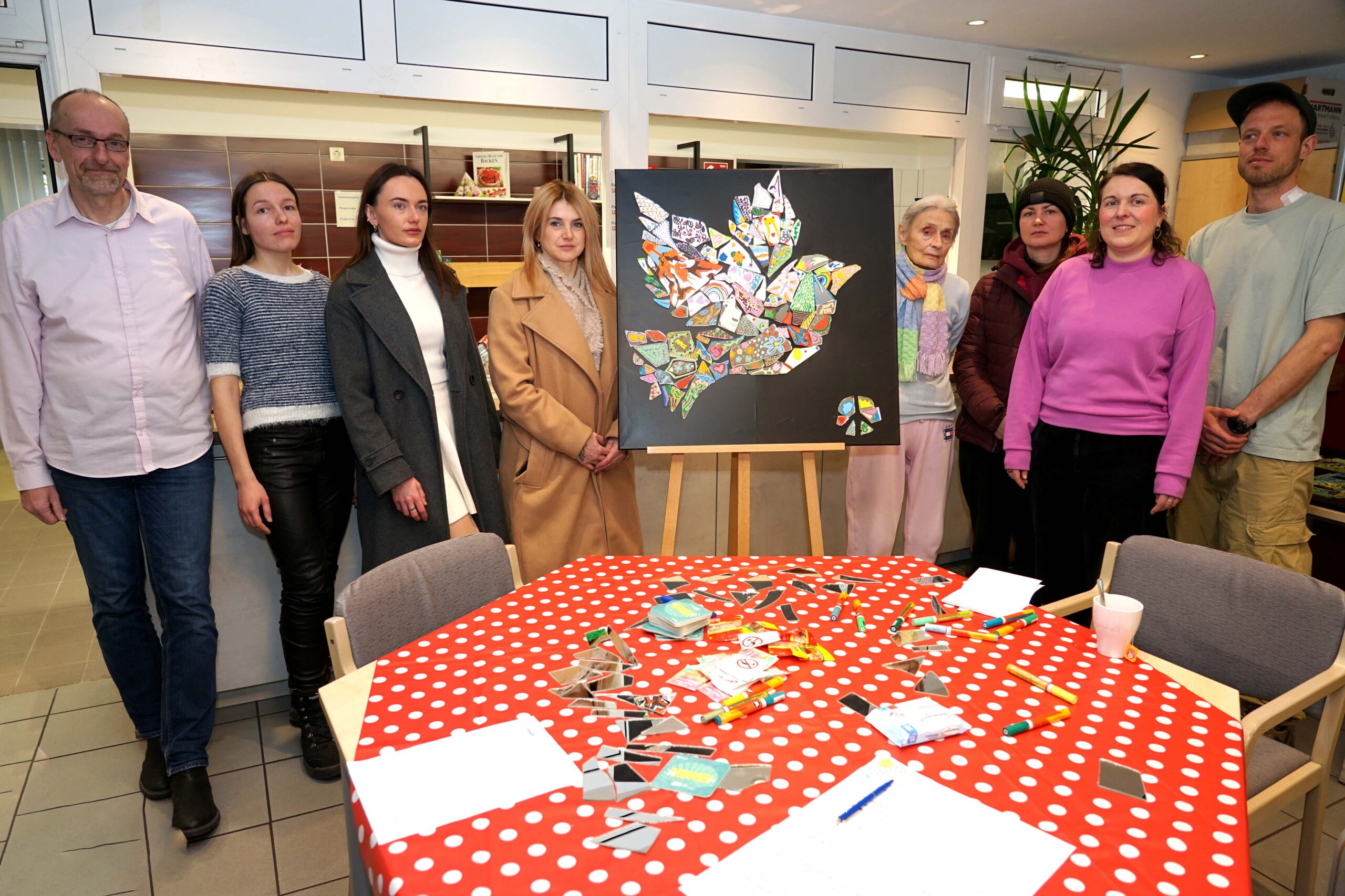 Bilder aus Spiegelscherben konnten Geflüchtete aus der Ukraine im Bernhard-März-Haus der Caritas Dortmund erstellen. Diese Ukrainerinnen freuten sich über die Aktion, die von Einrichtungsleiter Frank Merkel (1.v.l), Kristina Sobiech von youngcaritas Dortmund (2.v.r.) und dem Künstler Hendryk von Busse (1.v.r.) begleitet wurde. Foto: Michael Bodin / Erzbistum Paderborn