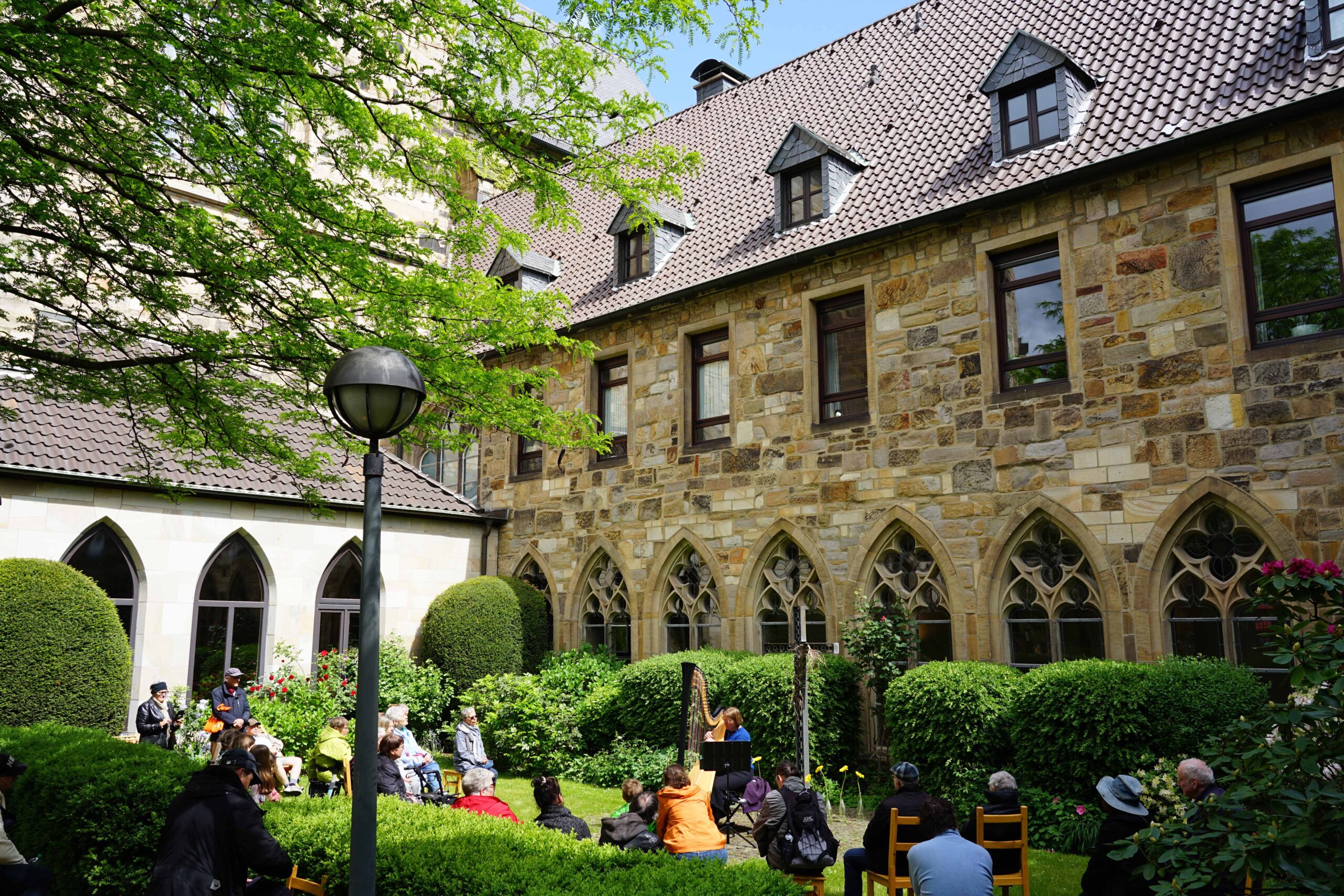 Zu den Klängen der von Luzinde Hahne gespielten Harfe genossen die Besucherinnen und Besucher des Klostergartens im Propsteihof die ruhige Atmosphäre dort. Foto: Michael Bodin / Kath. Pressestelle Dortmund