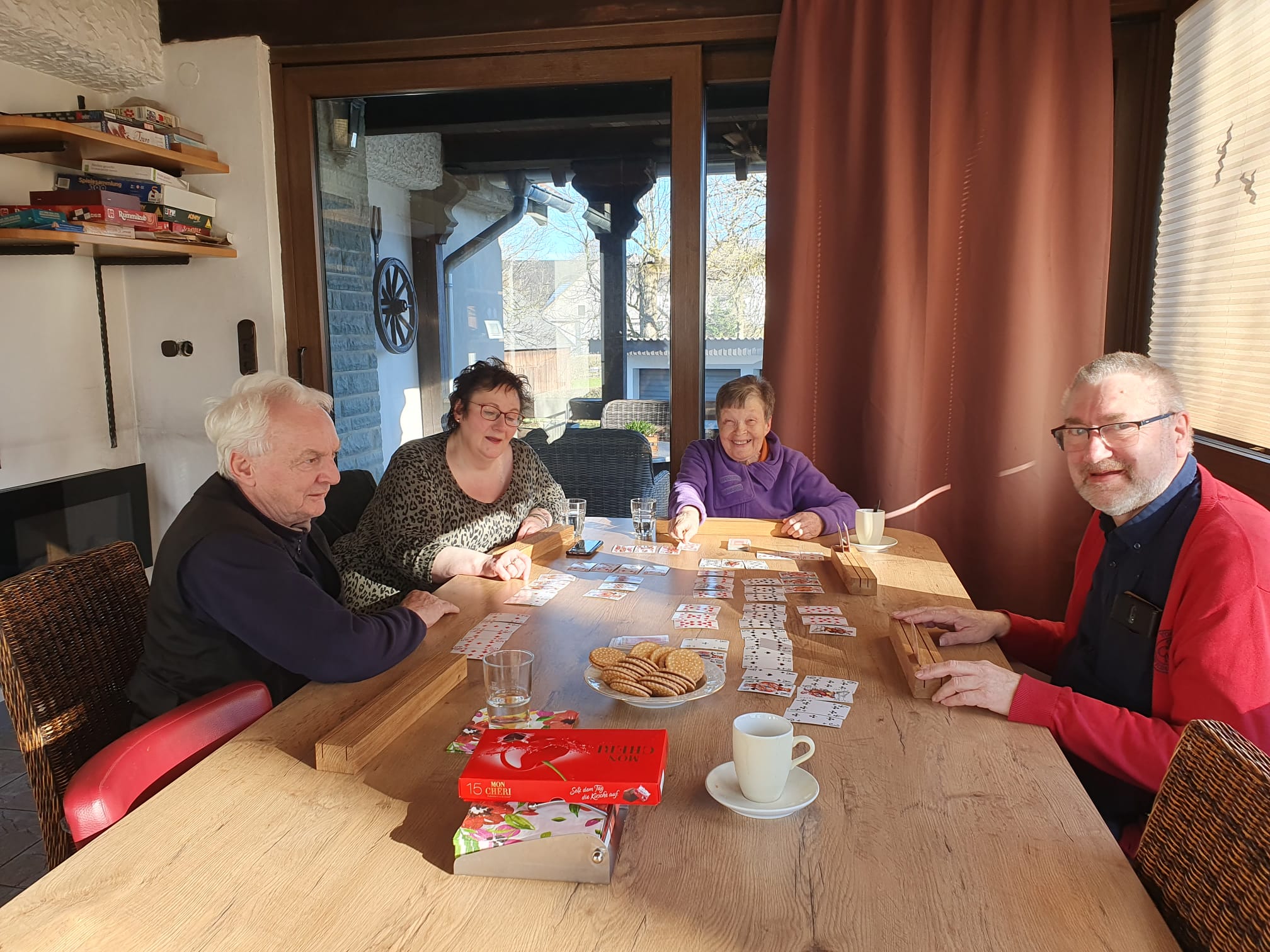 Ältere Menschen sitzen um einen Tisch herum und spielen Karten.