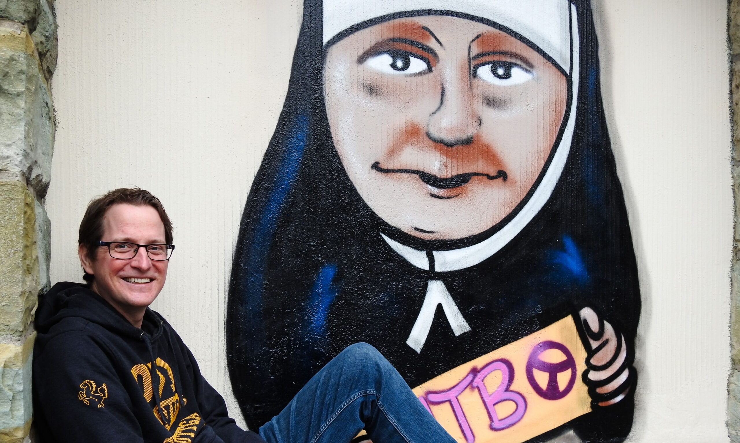 Christoph Scheppe vor dem Graffiti der Ordensgründerin Maria Theresia Bonzel.
