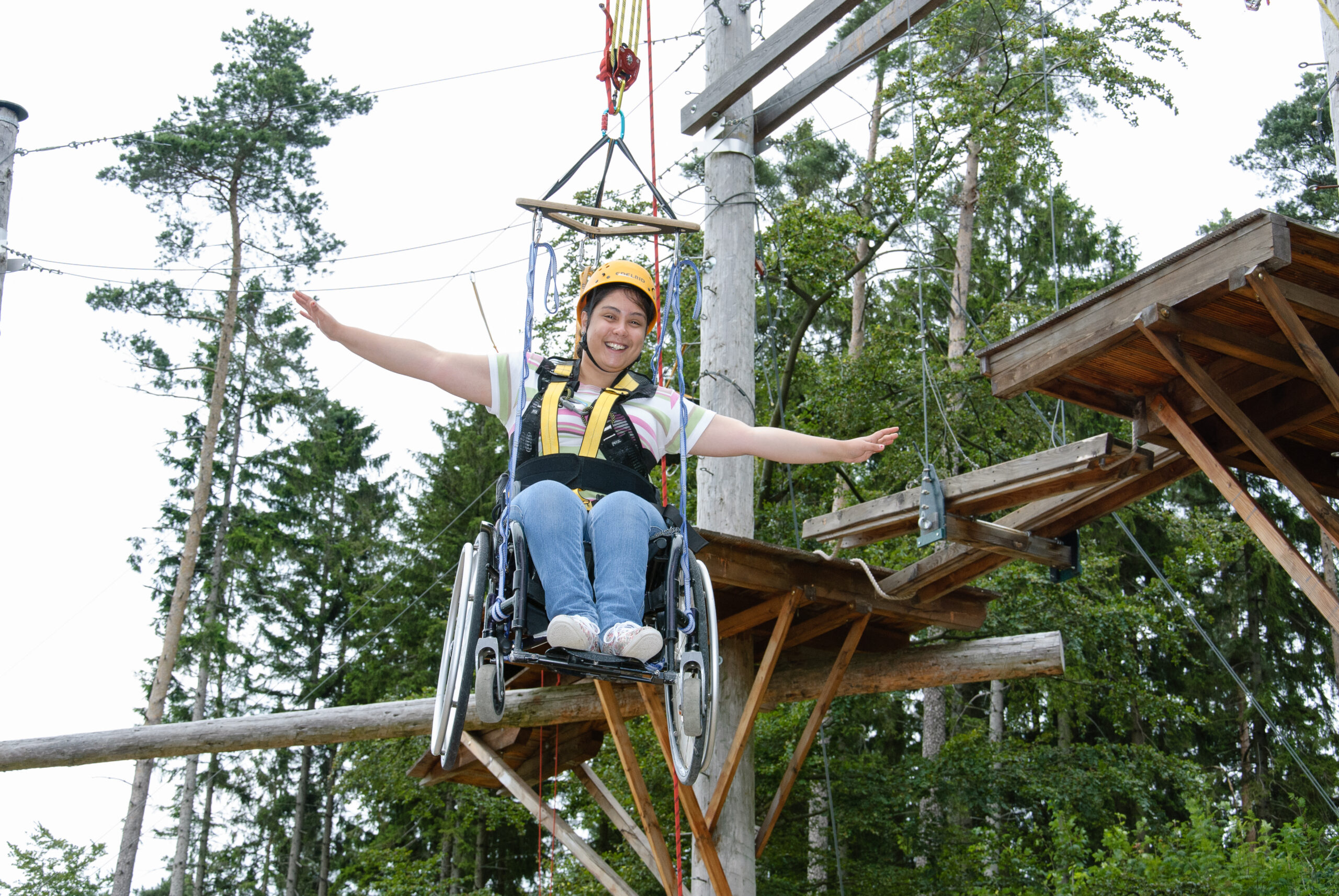 Ein Frau angegurtet im Hochseilgarten - das erfordert Mut.