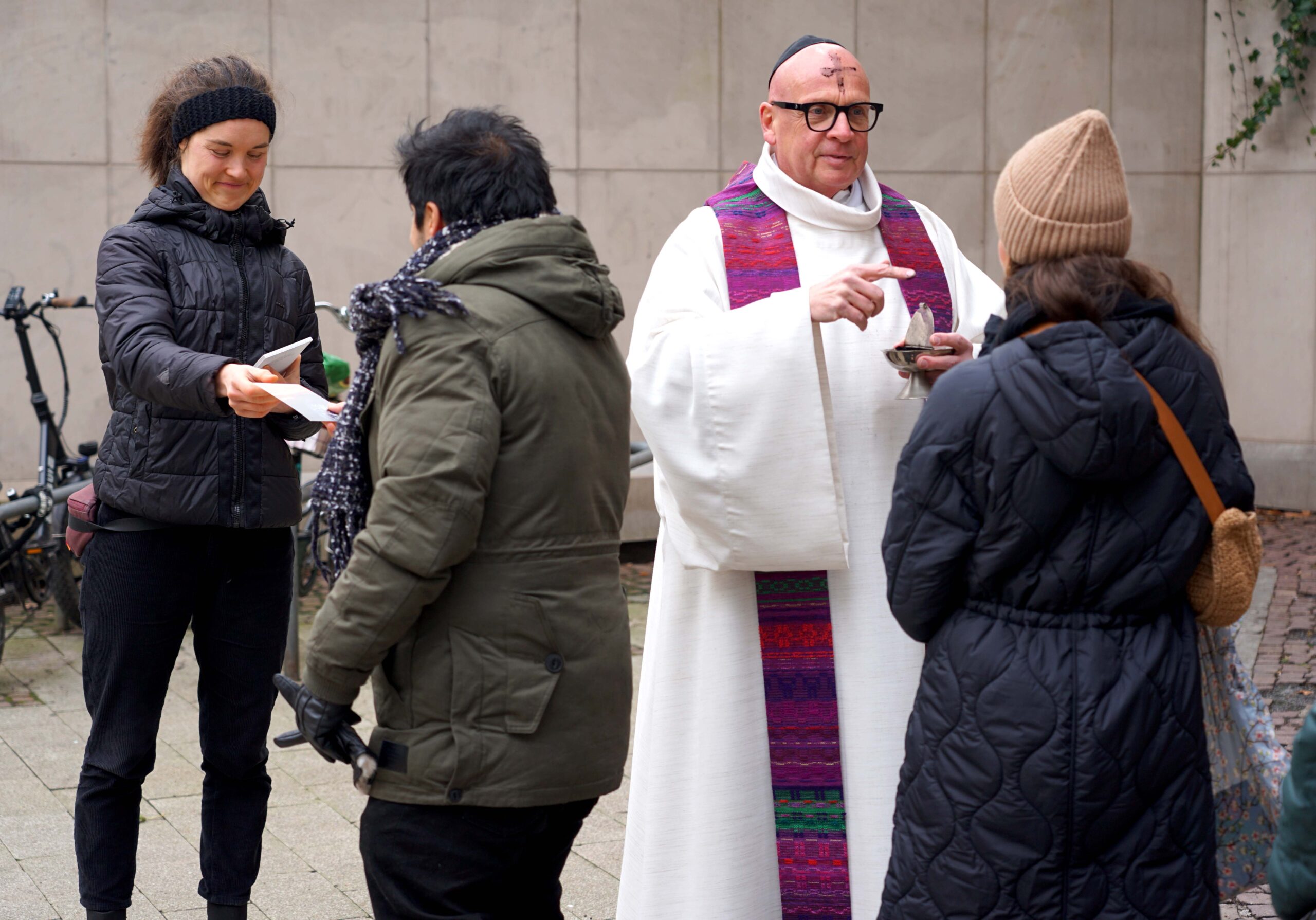: Pastor Stefan Tausch verteilte auf dem Platz von Hiroschima das Aschekreuz unter freiem Himmel. Thale Schmitz (links) vom Katholischen Forum gab den Besucherinnen und Besuchern eine Karte mit einer Losung für die Fastenzeit. Foto: Michael Bodin / Katholische Pressestelle Dortmund