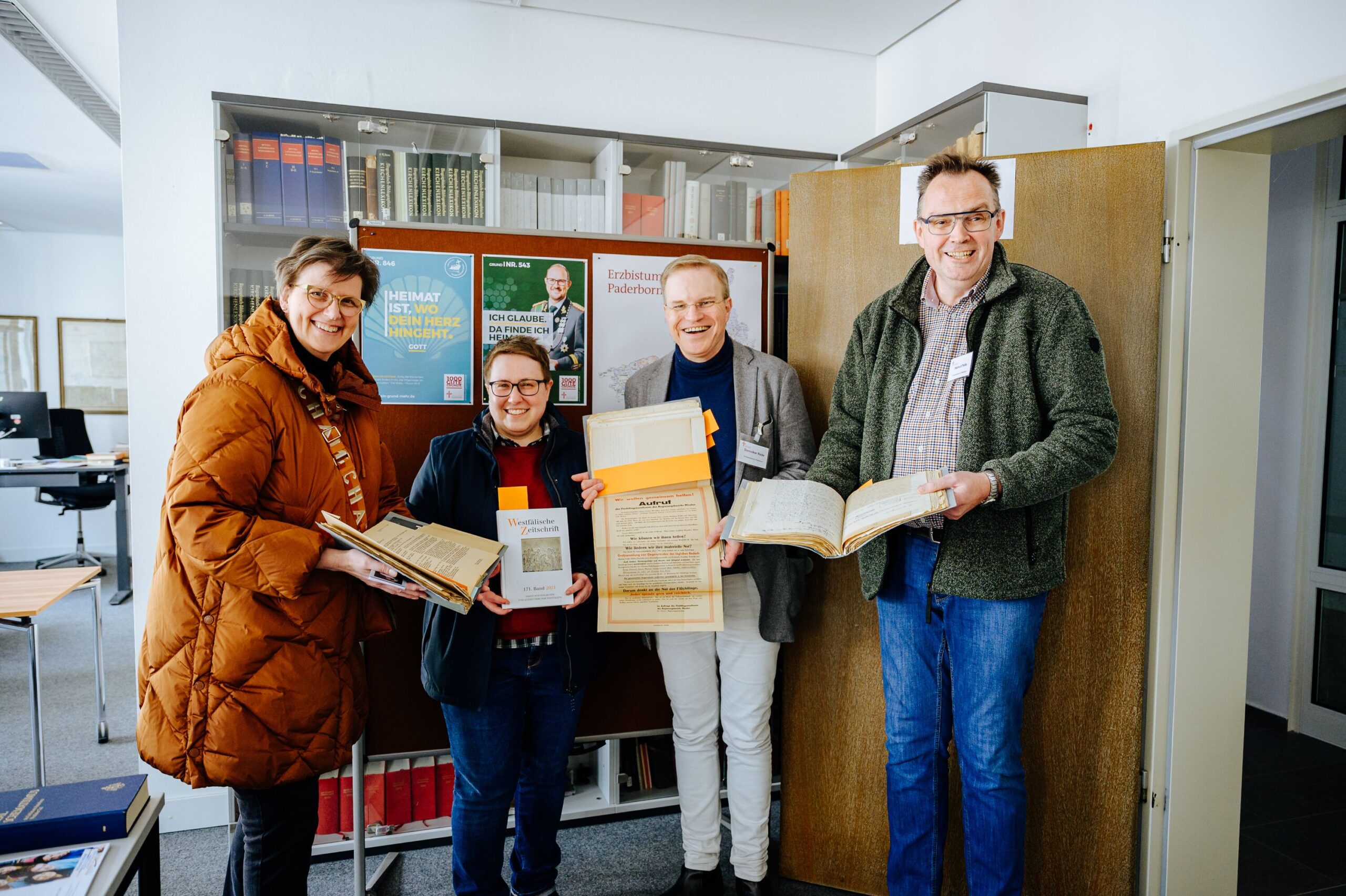 Besucherinnnen und Mitarbeitr zeigen Archivalien.