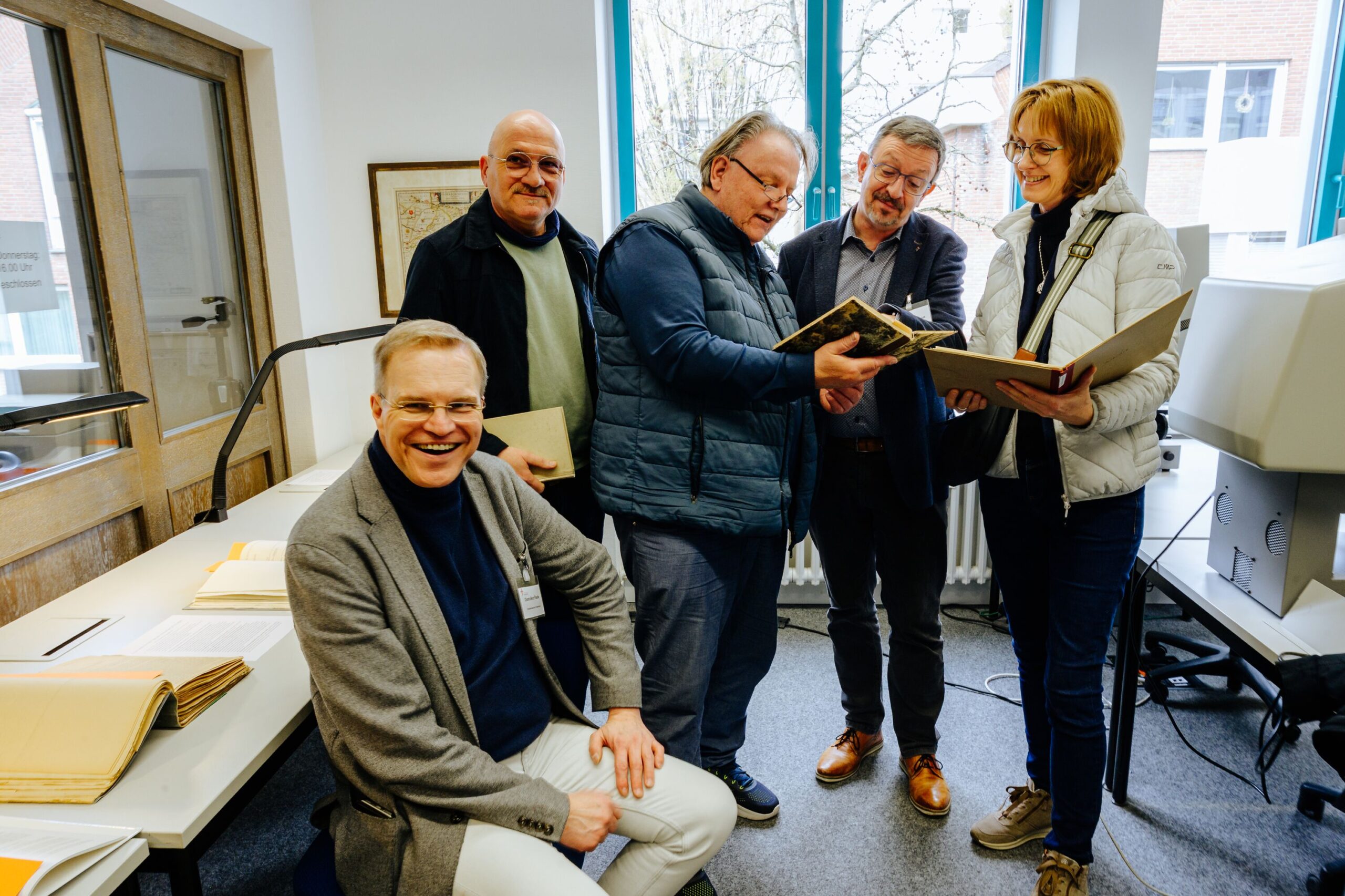 Besuchergruppe blätter im Lesesaal in Akten und Büchern aus dem Archiv.