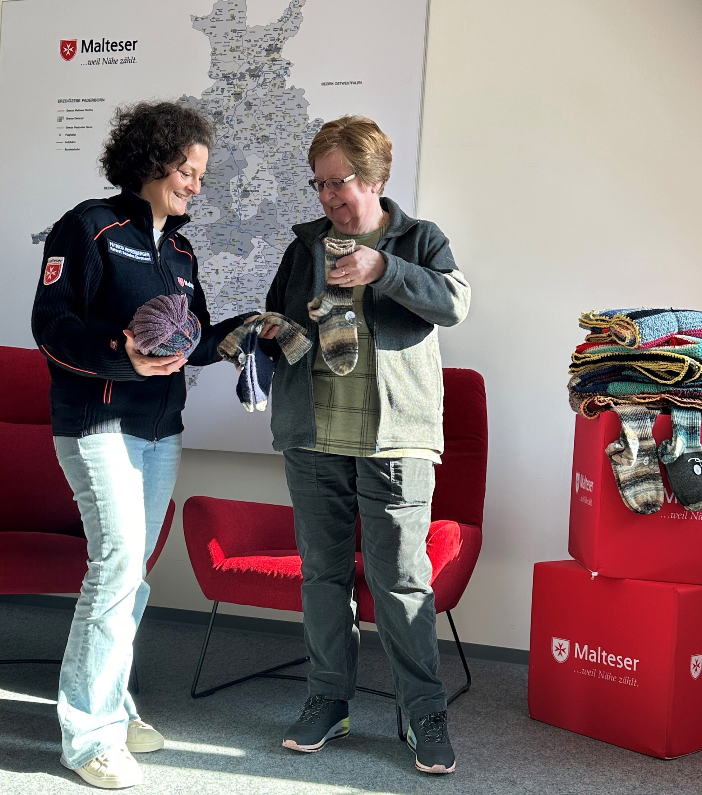 Malteser: Marieta Meyer (rechts) von der Strickgruppe der Caritas-Konferenz St. Johannes in Salzkotten übergab gestrickte Mützen, Schals und Socken an Patricia Hohenberger von den Maltesern im Erzbistum Paderborn für Menschen ohne Krankenversicherung sowie für die Klienten des Malteser Wärmebusses.