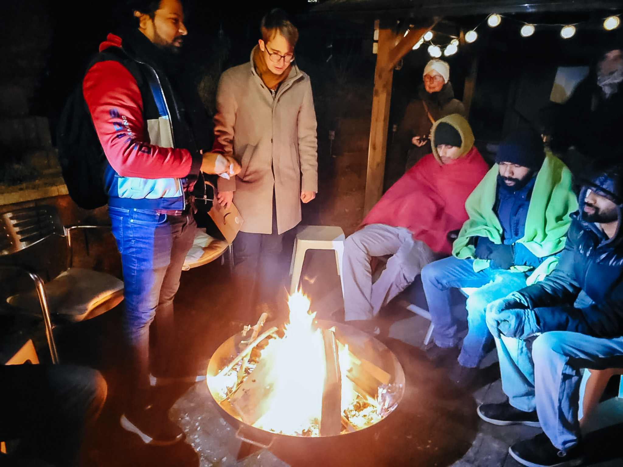 Mitglieder von Come and see stehen gemeinsam an einem Feuer.