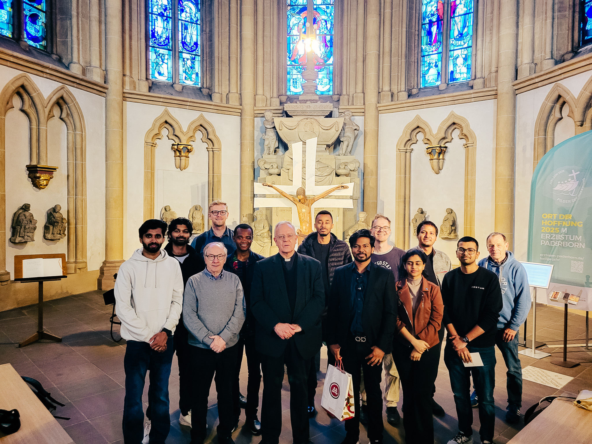 Mitglieder von Come and see stehen gemeinsam in einer Kirche zusammen; zur Gruppe gehören Menschen aus 26 Nationen.