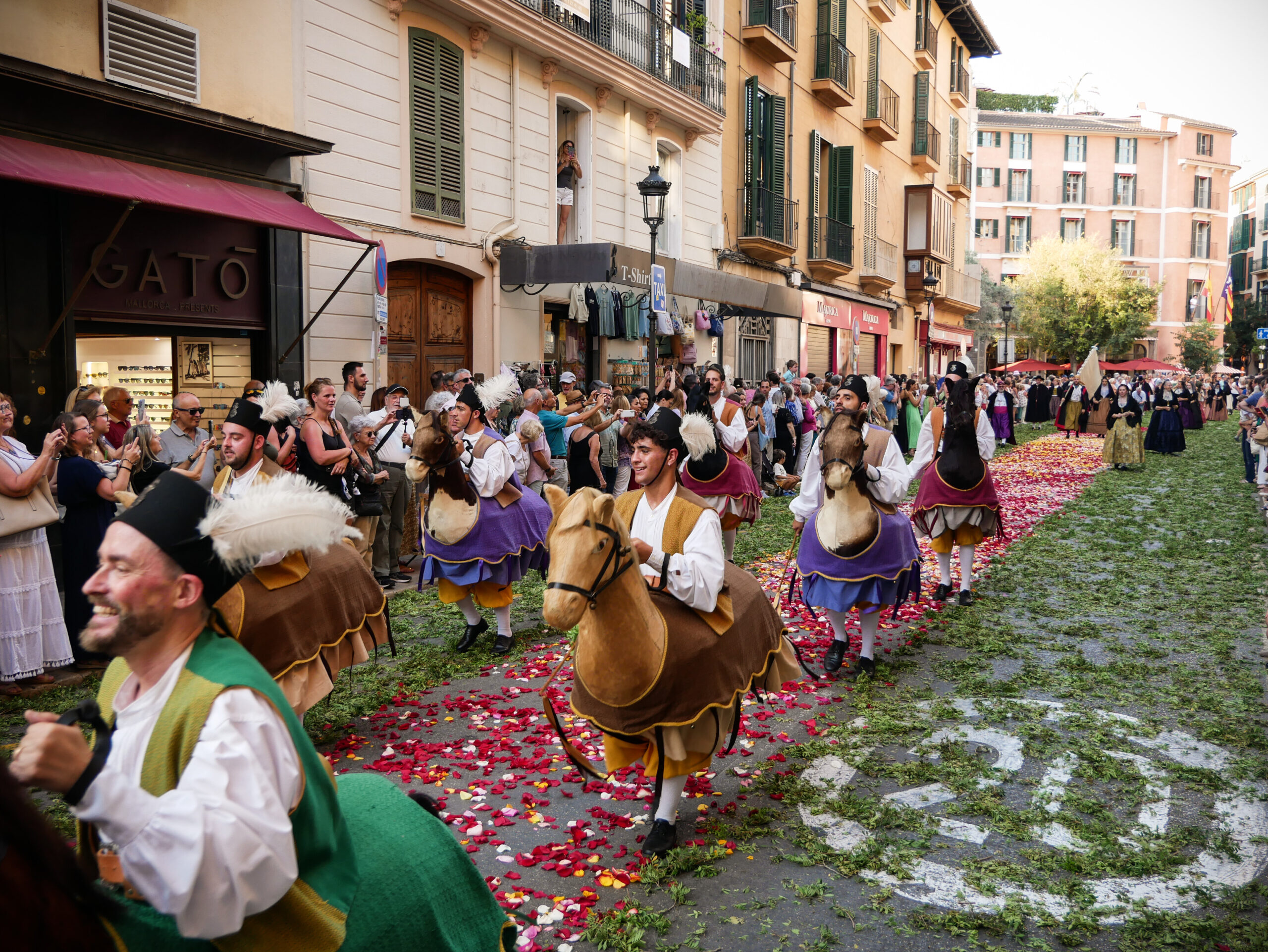(2) Menschen mit traditionellen Pferdekostümen laufen über den Blütenteppich bei der Fronleich-namsprozession am 22. Juni 2025 in den Straßen von Palma de Mallorca (Spanien).