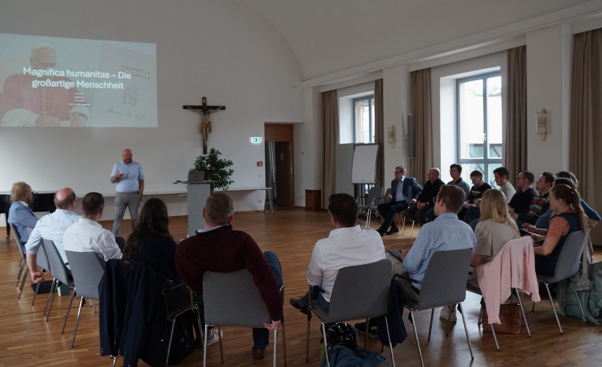 Intensives Gespräch über die Enzyklika Papst Leos in der Aula des Leocampus zwischen den Teilnehmenden und Prof. Dr. Aaron Langenfeld (l.)