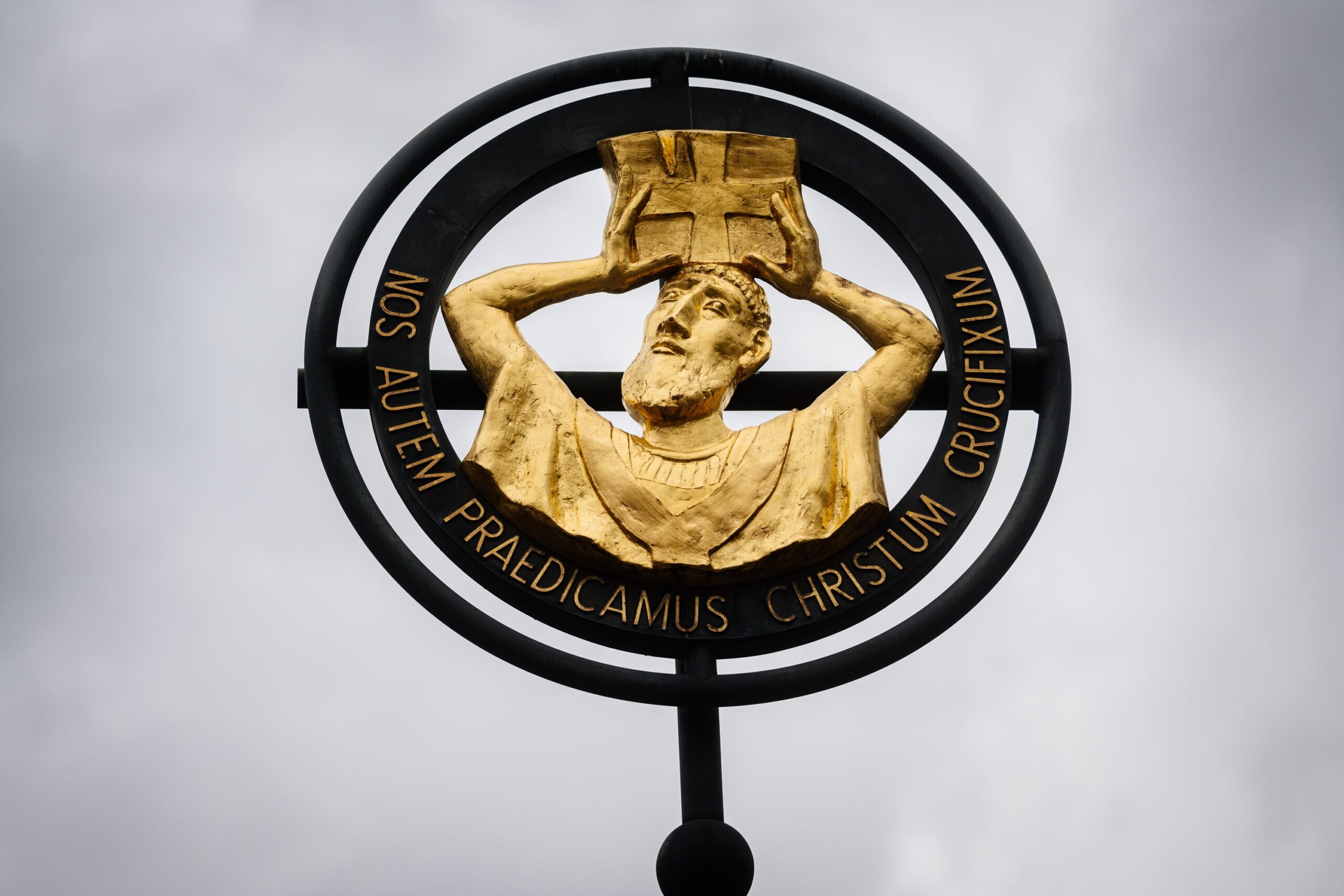 Eine goldene Figur mit einem Buch auf dem Kopf in einem dunklen Metallring