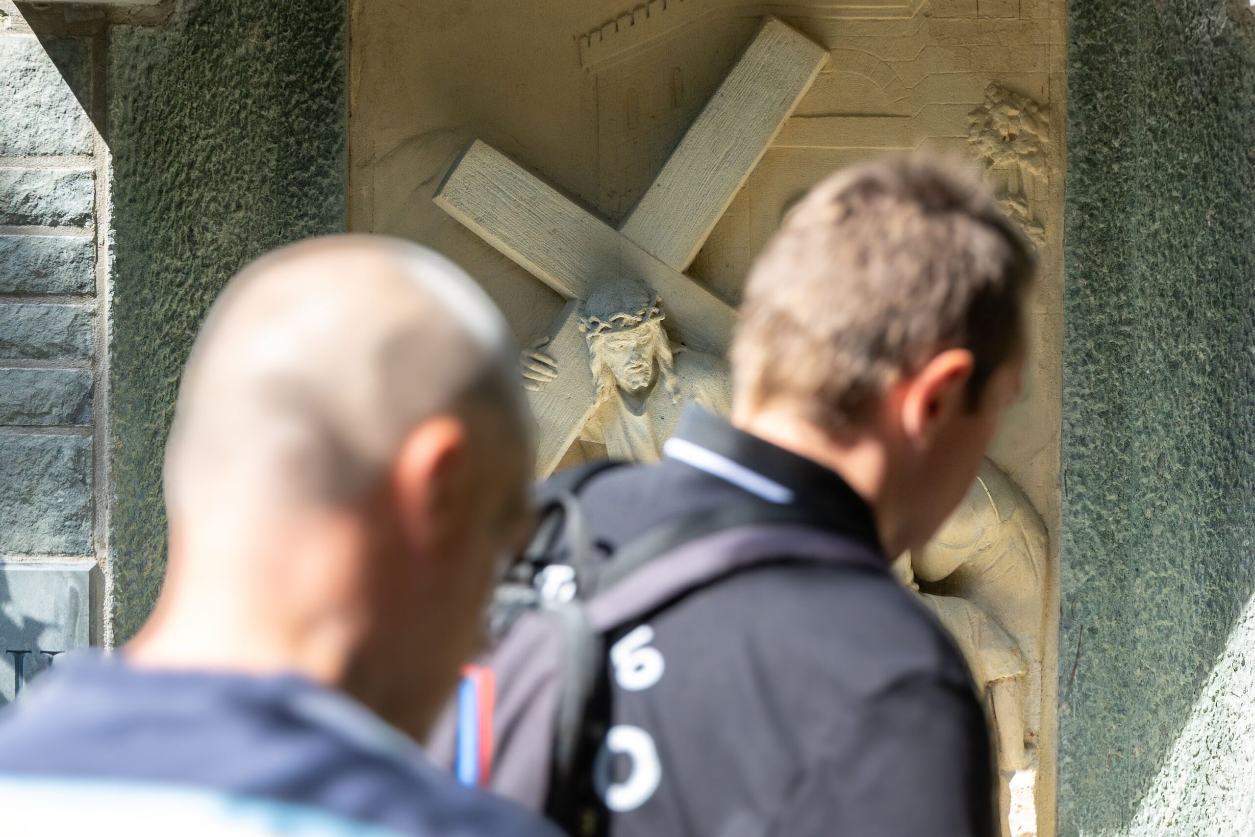 Zwei an der Wallfahrt teilnehmende Männer sind von hinten fotografiert.