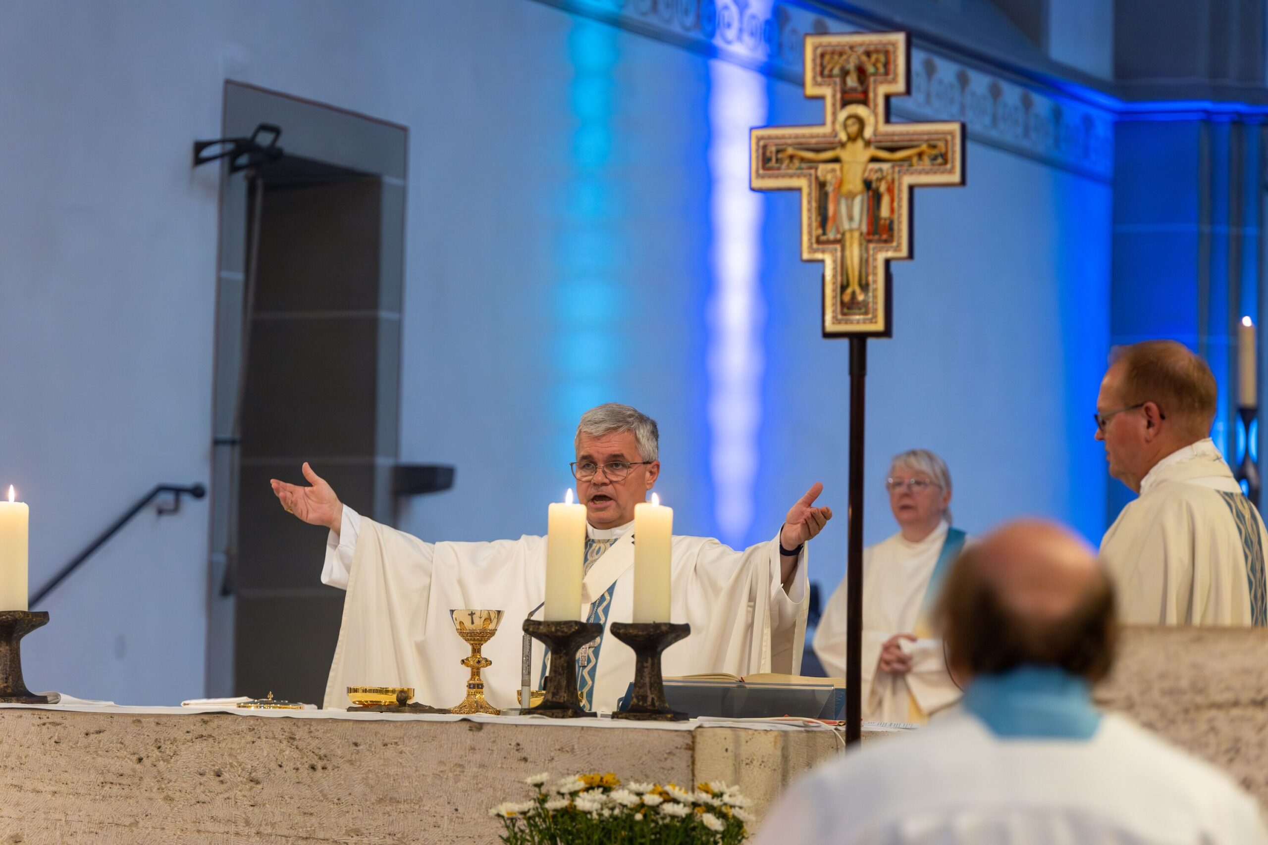Der Erzbischof zellibriert die Messe am Altar und streckt die Arme aus.