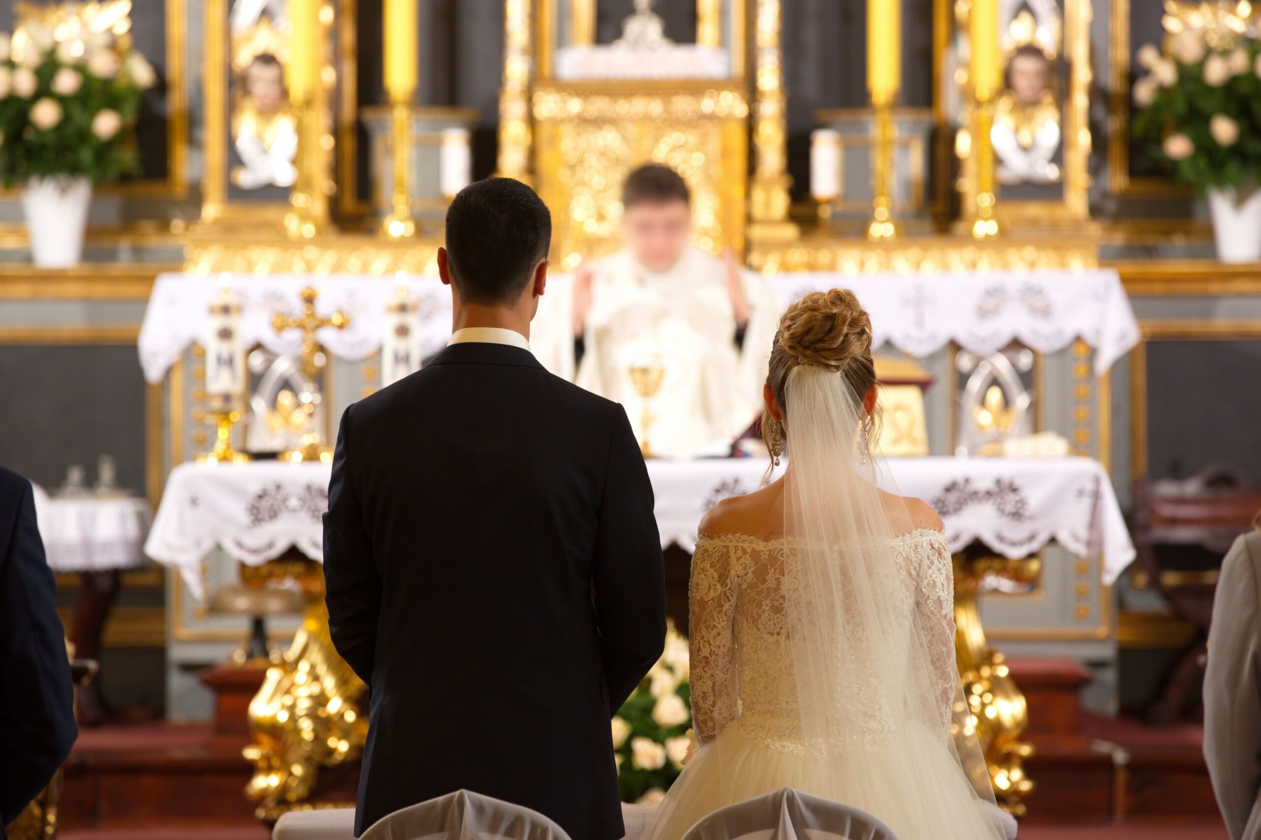 Rückenansicht eines Brautpaars vor dem Altar und Priester