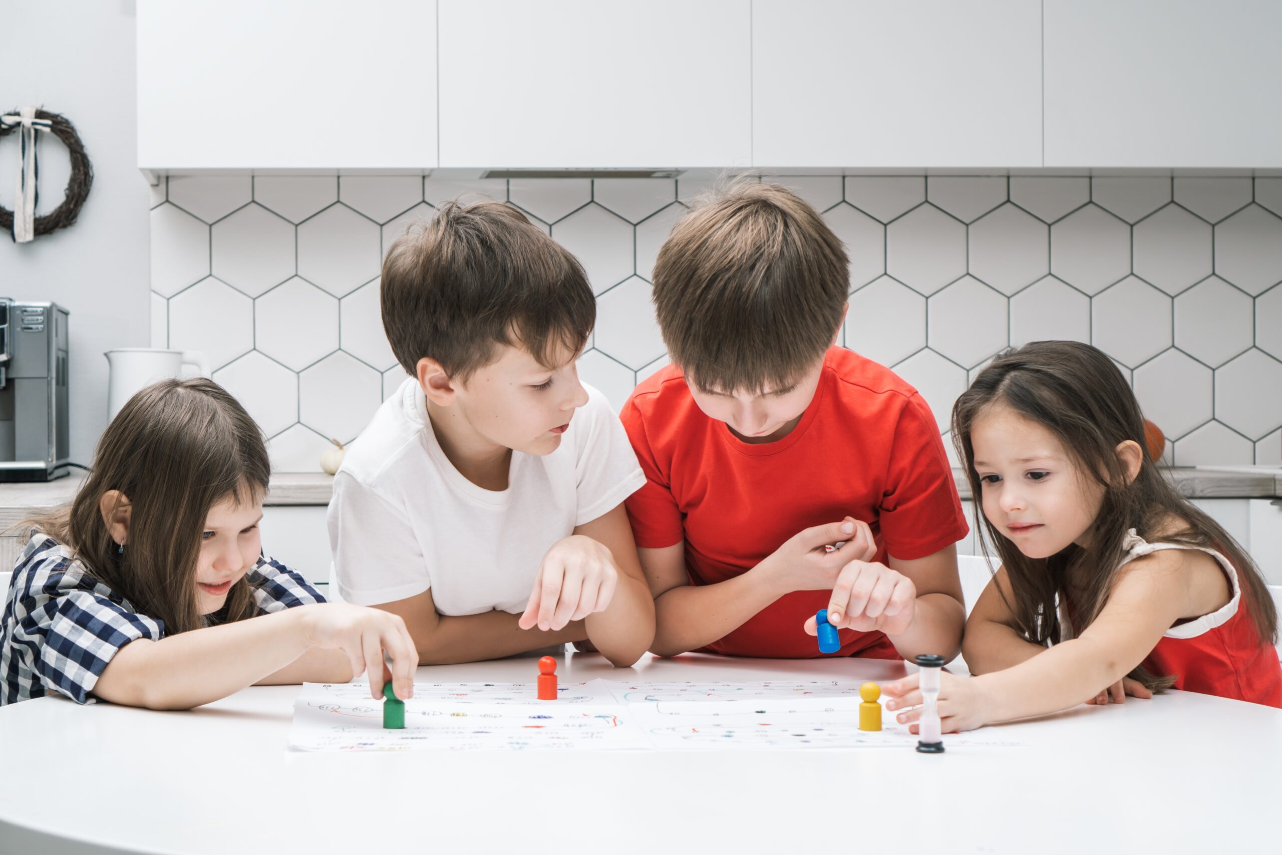 Vier Kinder spielen in der Küche zusammen ein Brettspiel