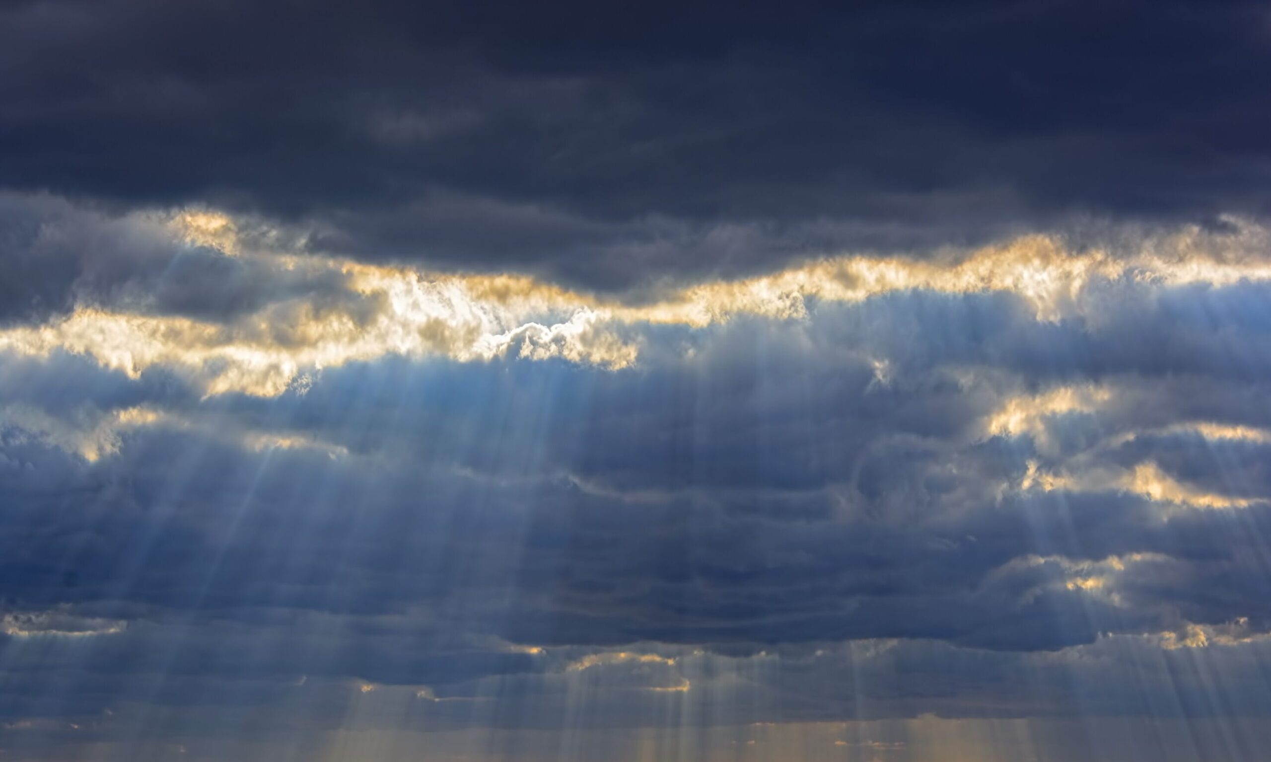 Im Himmel reißen die Wolken auf und Licht scheint hindurch