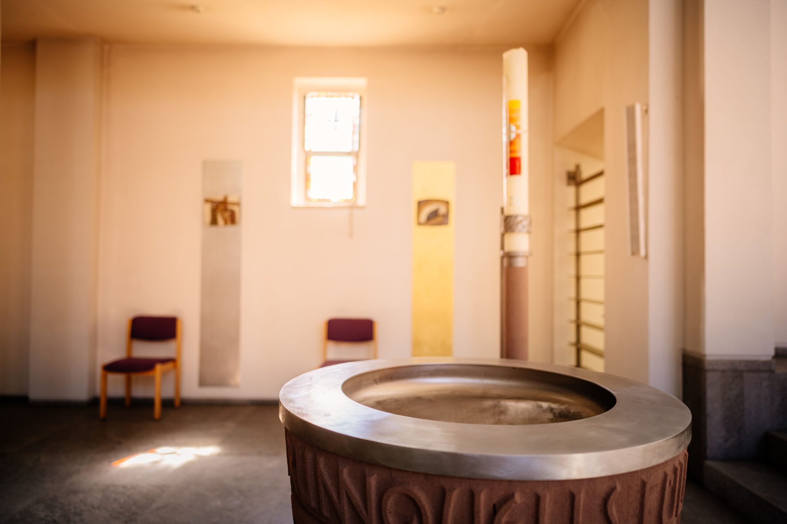 Ein Taufbecken in einer hell erleuchteten schlichten Kirche