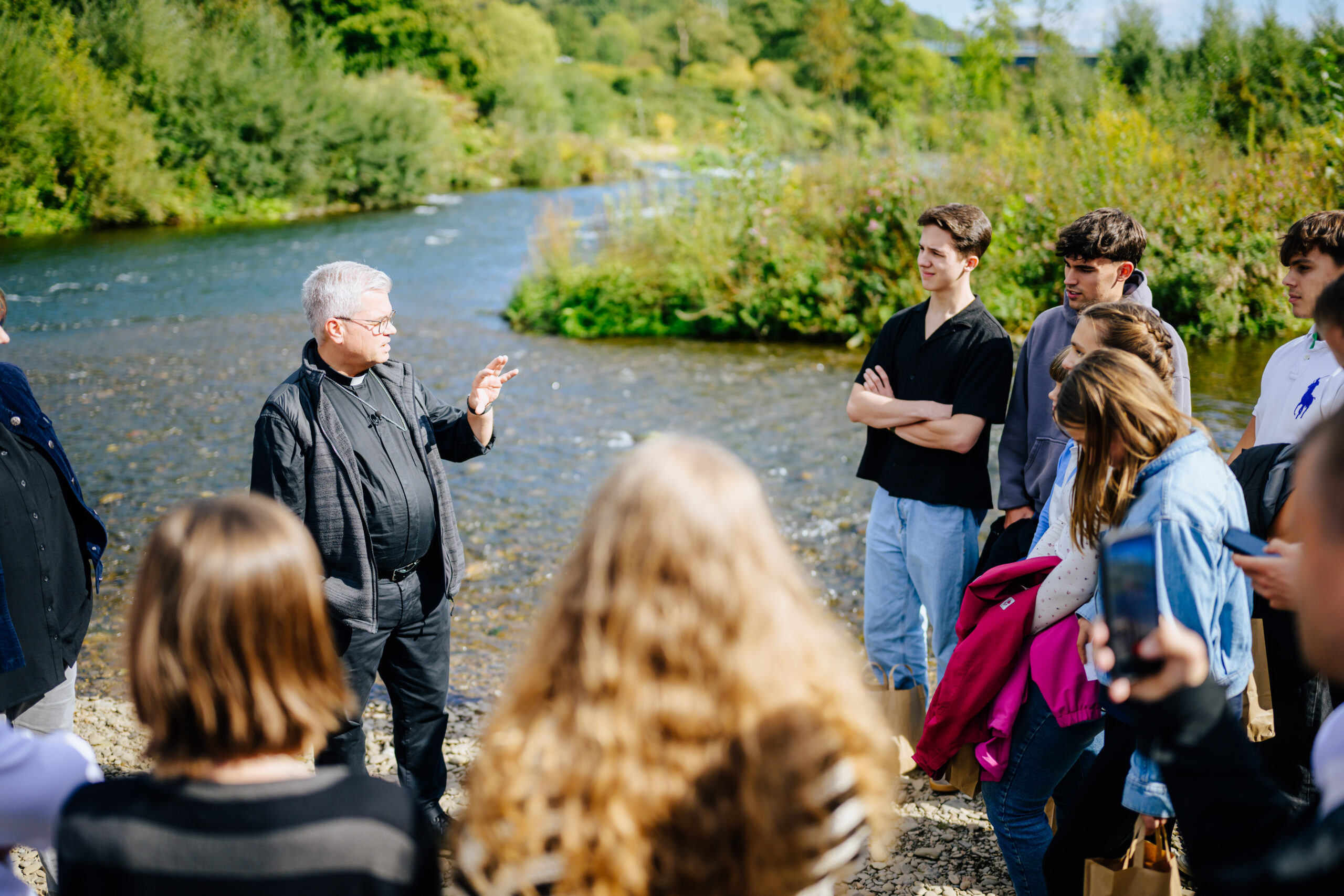 Erzbischof Dr. Udo Markus Bentz am Ufer der Lenne im Gespräch mit Schülerinnen und Schüler der Hildegardis-Schule in Hagen.